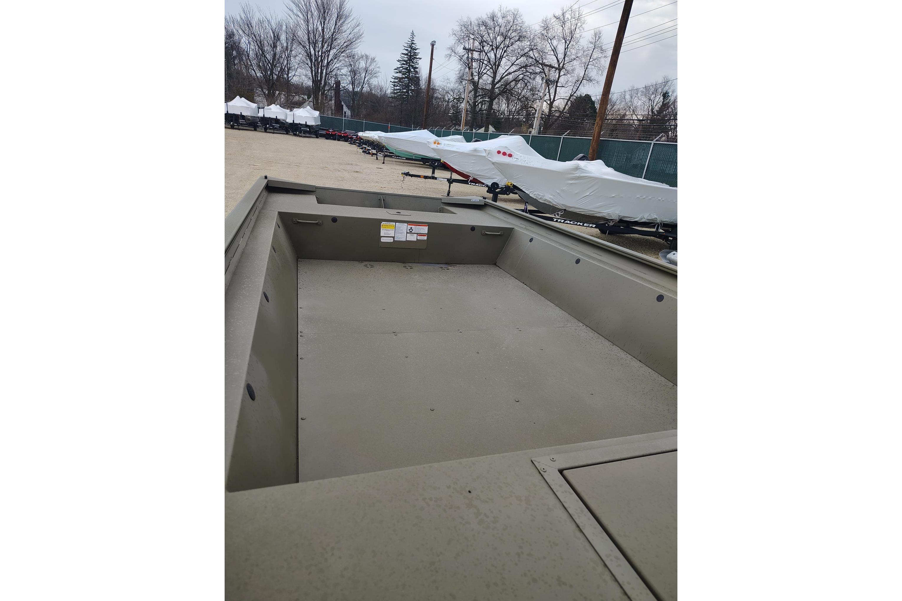 2025 Tracker Grizzly 1860 Utility boat in storage yard, surrounded by covered boats.