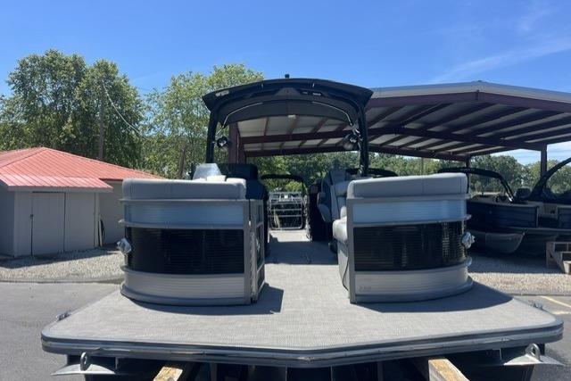 2024 Manitou 25 LX SRW pontoon boat in a marina under clear blue skies.