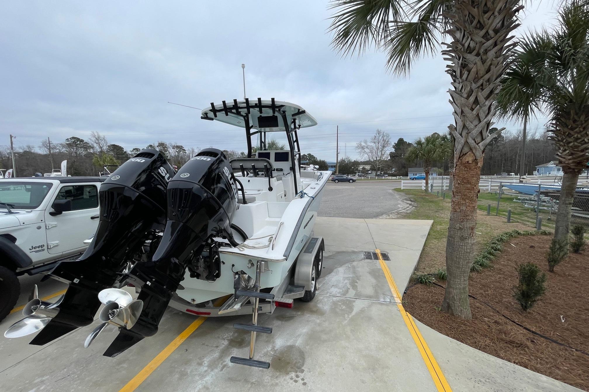 2023 Cape Horn 24 XS boat with dual Suzuki outboard motors, parked near palm trees.