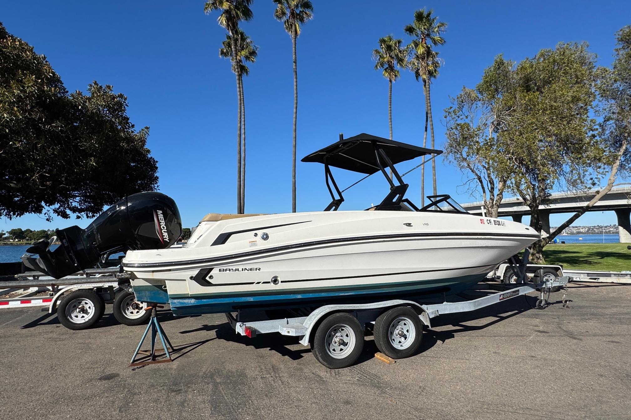 2022 Bayliner VR6 Bowrider OB on trailer, parked near palm trees and water.