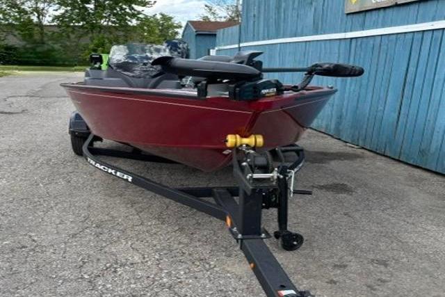 2025 Tracker Super Guide V-16 SC boat on trailer, parked by blue building.