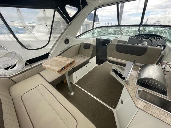 Interior of 2014 Sea Ray 310 Sundancer boat with seating, table, and helm.