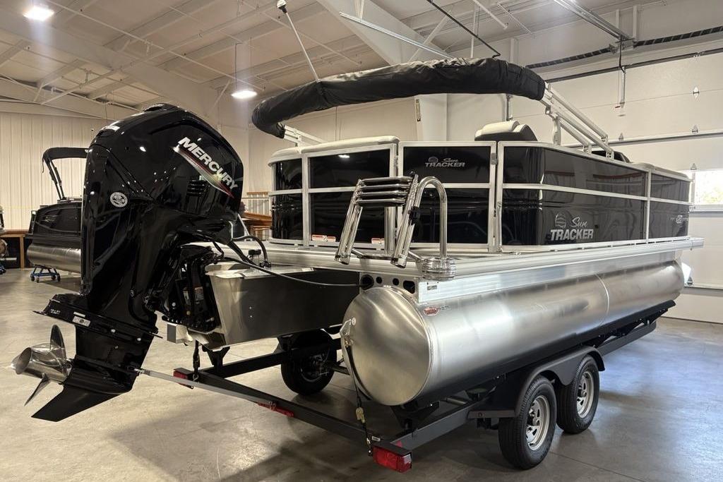 2026 Sun Tracker PARTY BARGE® 20 DLX pontoon boat with Mercury outboard motor in a showroom.