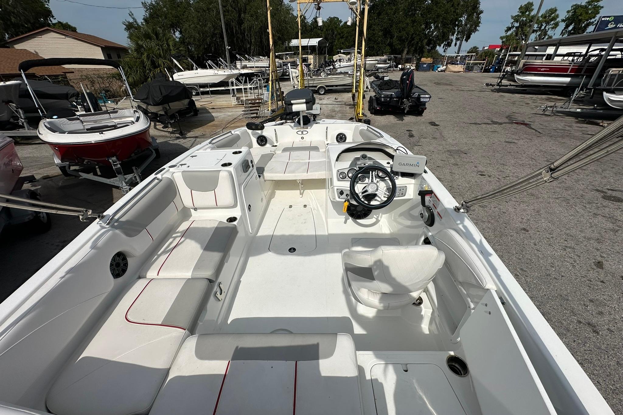 2021 Tahoe 2150 boat interior with steering wheel and seating, parked in a marina.