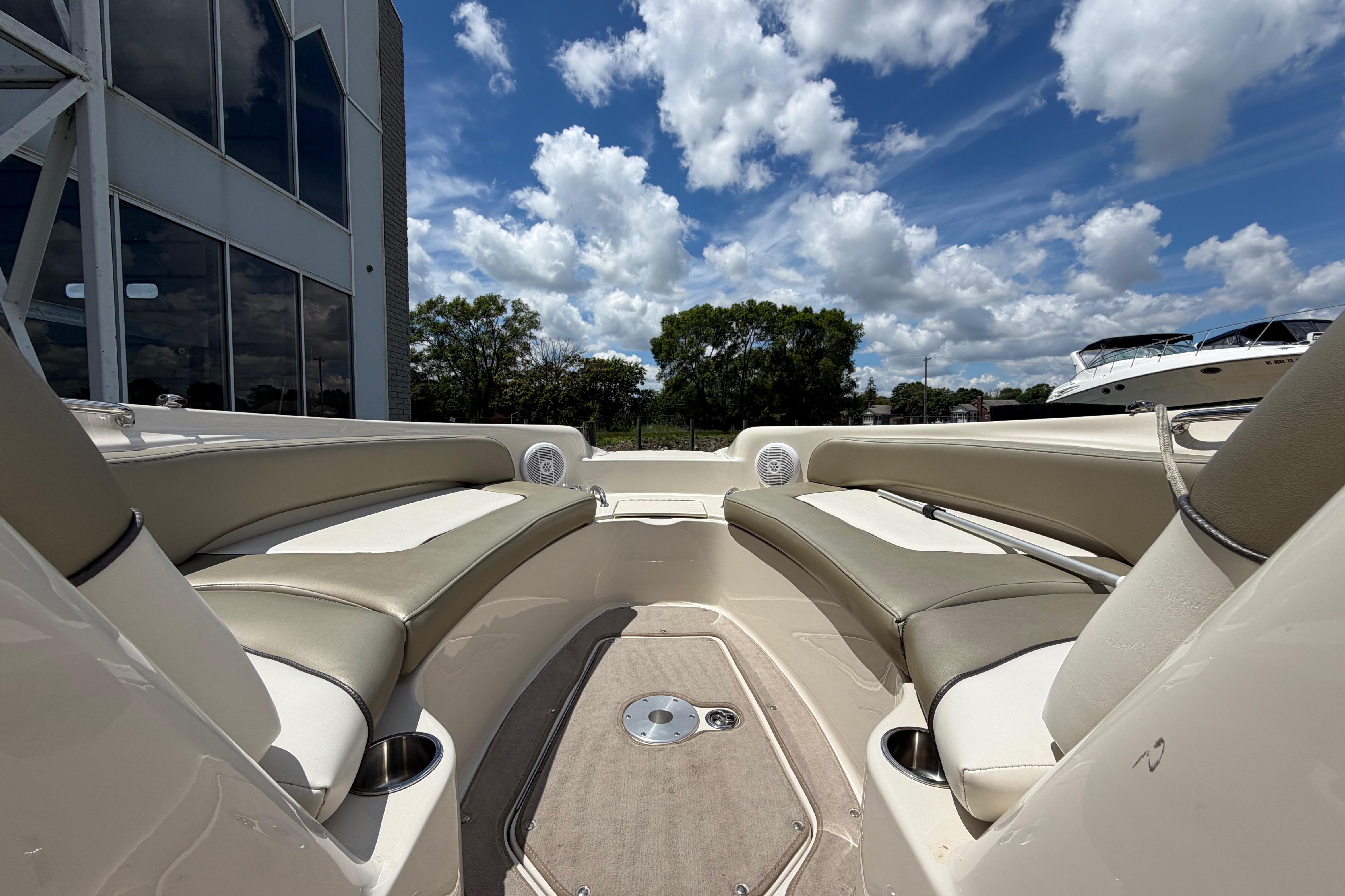 2004 Sea Ray 240 Sundeck interior with beige seating, under a bright blue sky.