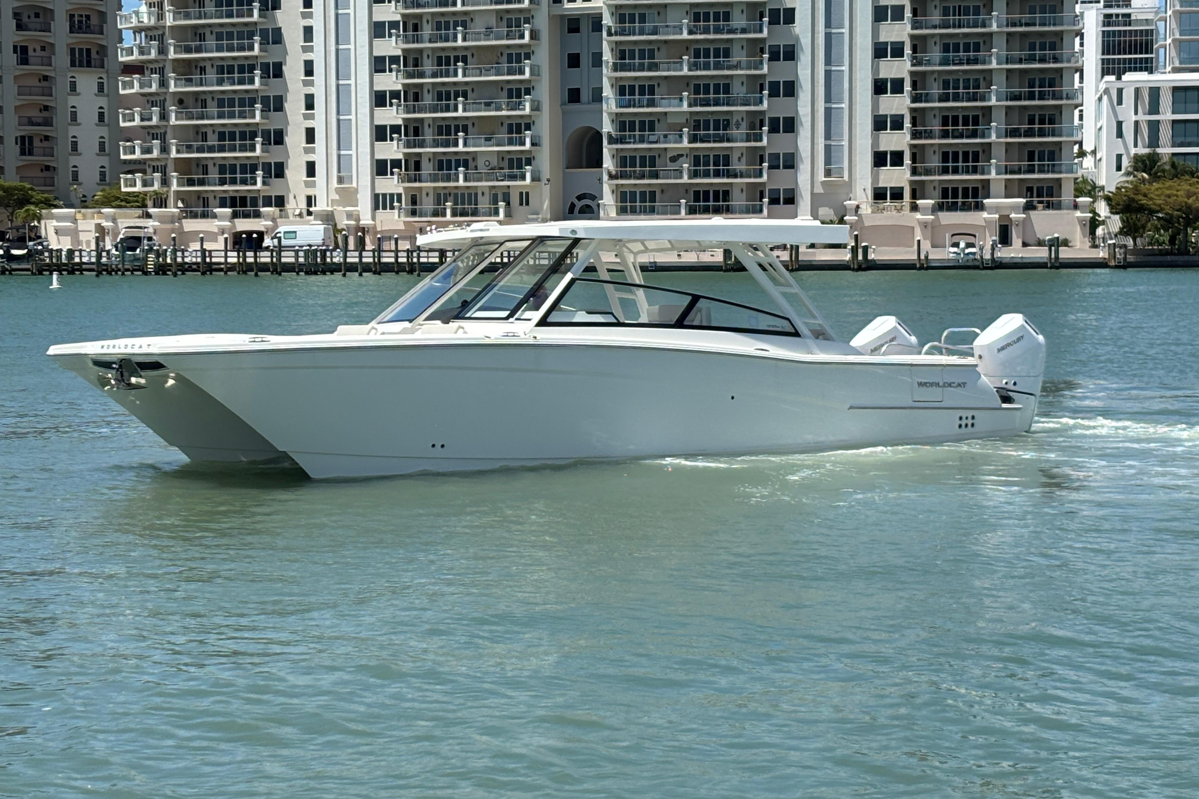 2026 World Cat 400 DC-X Island boat cruising near waterfront buildings.