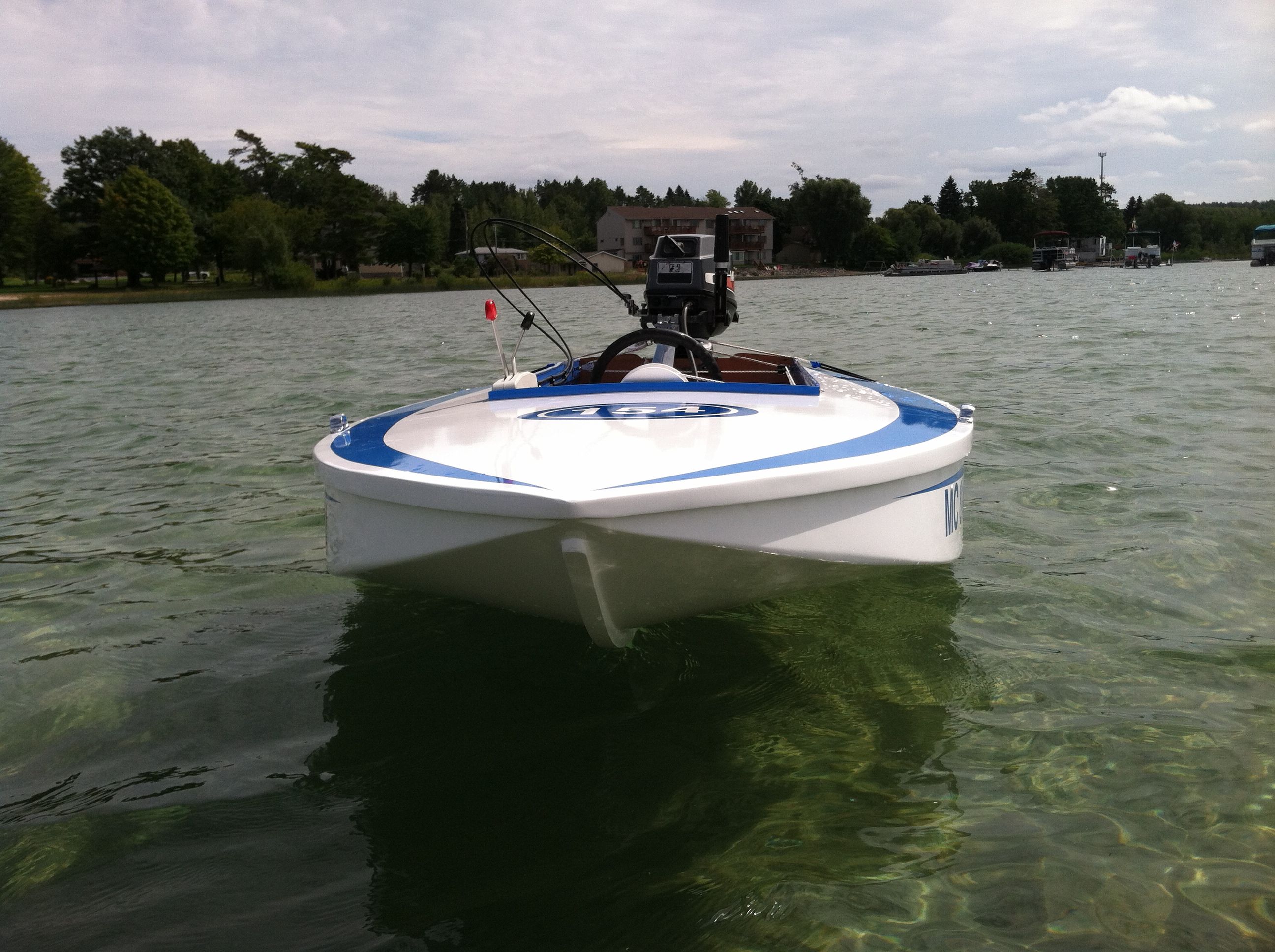A white racing boat with blue accents floats on clear water.