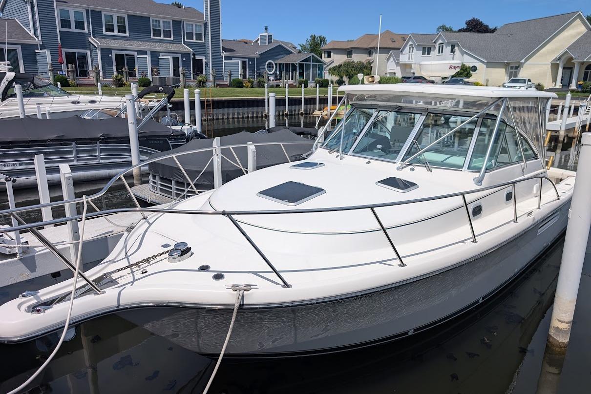 2000 Pursuit 3400 Express boat docked in a marina, surrounded by waterfront homes.
