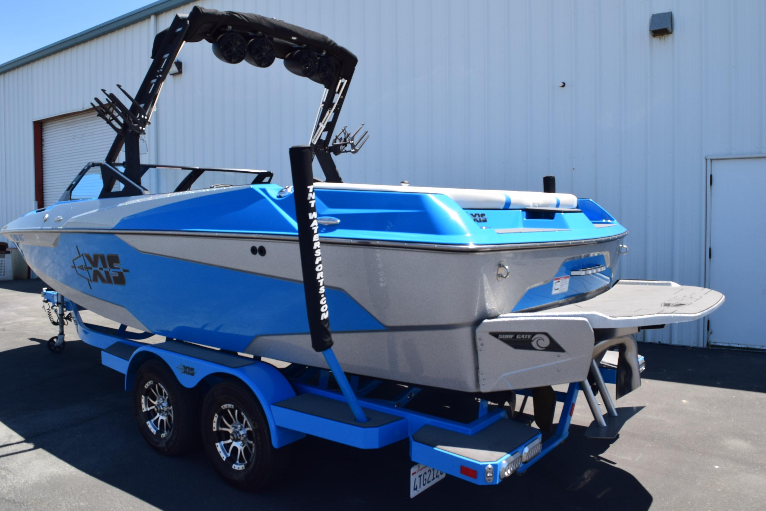 2019 Axis A22 boat in blue and gray on a trailer, parked outside a warehouse.