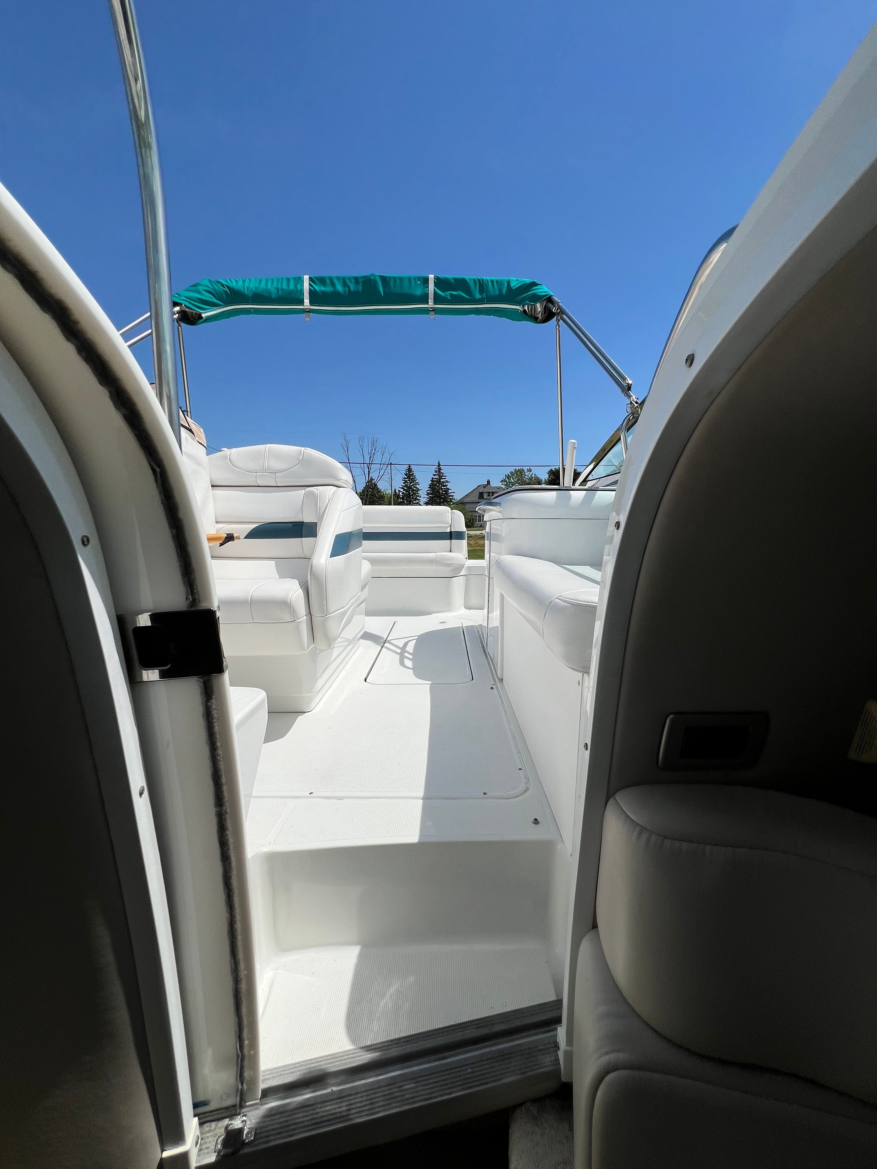 The image shows the cockpit of a 2005 Formula 260 Sun Sport with white seating and a green sunshade.