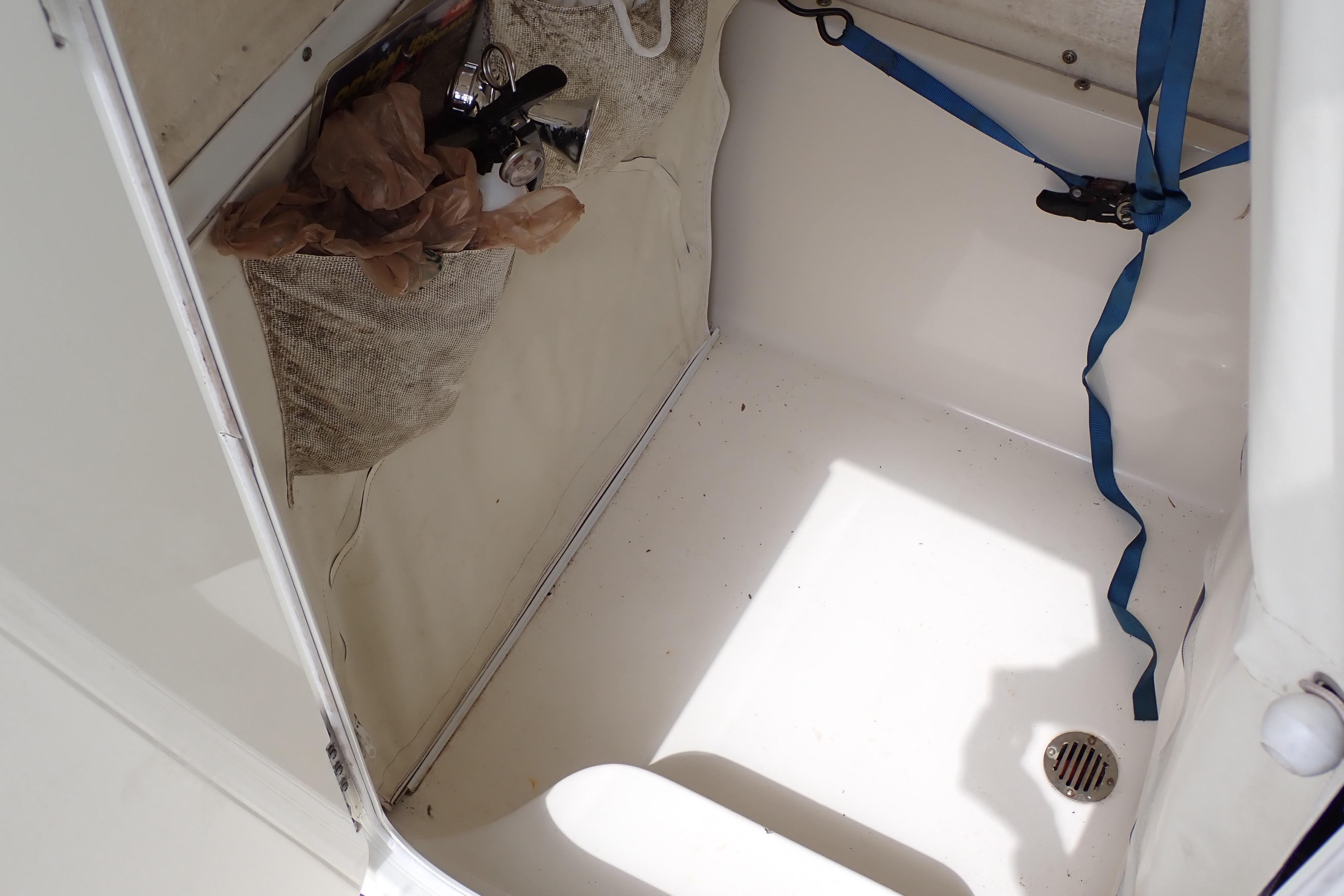 Interior storage compartment of 2019 Key West 263 FS boat with blue strap and drain.