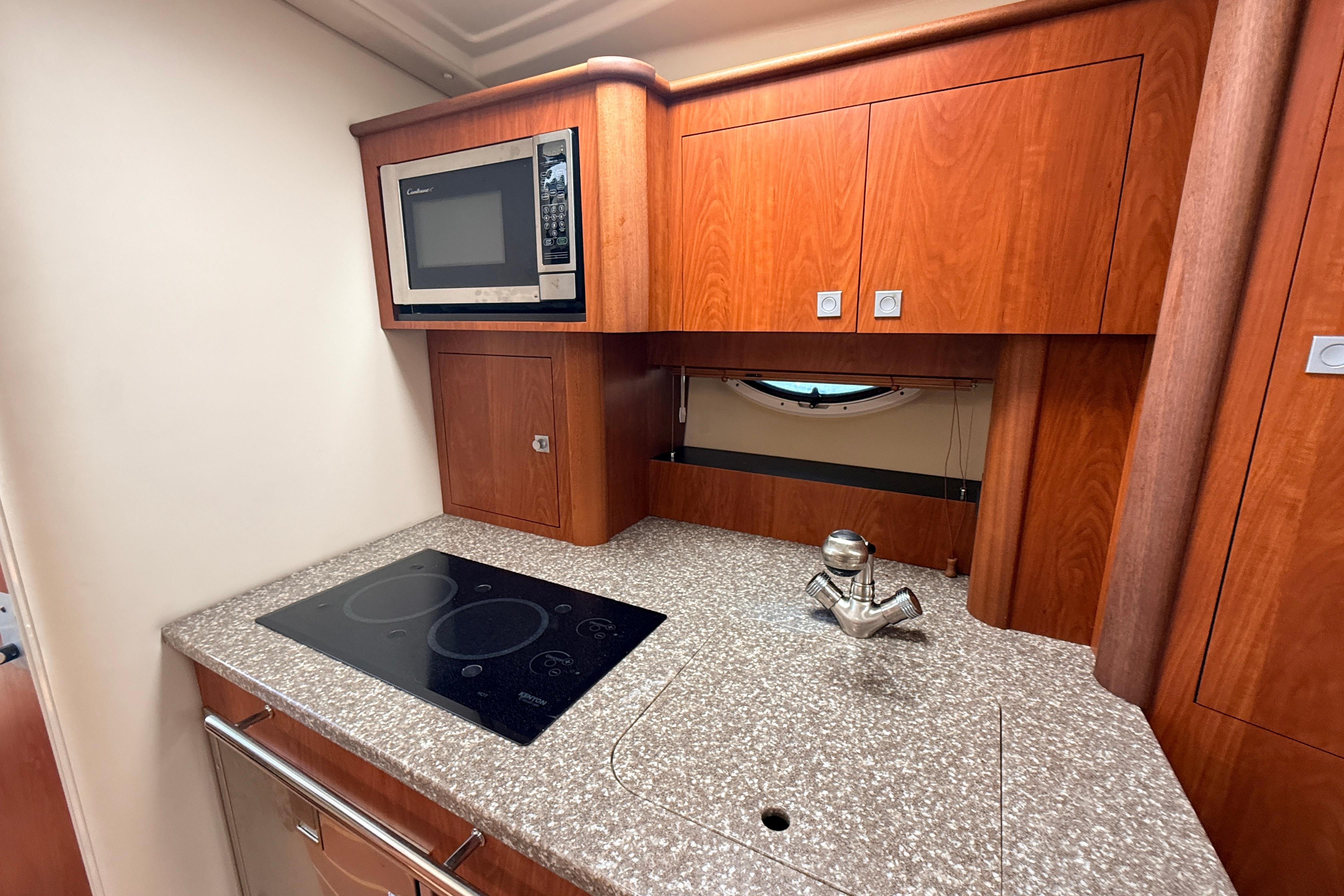 2011 Monterey 320 Sport Yacht kitchen with microwave, stovetop, and wood cabinetry.