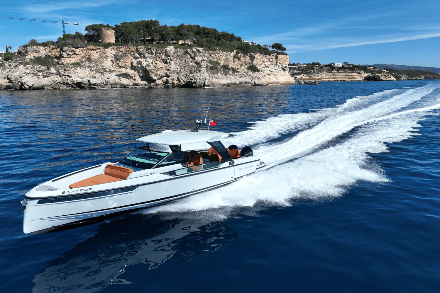 Saxdor SX320 GTO from 2027 cruising swiftly on calm water near a rocky coastline.