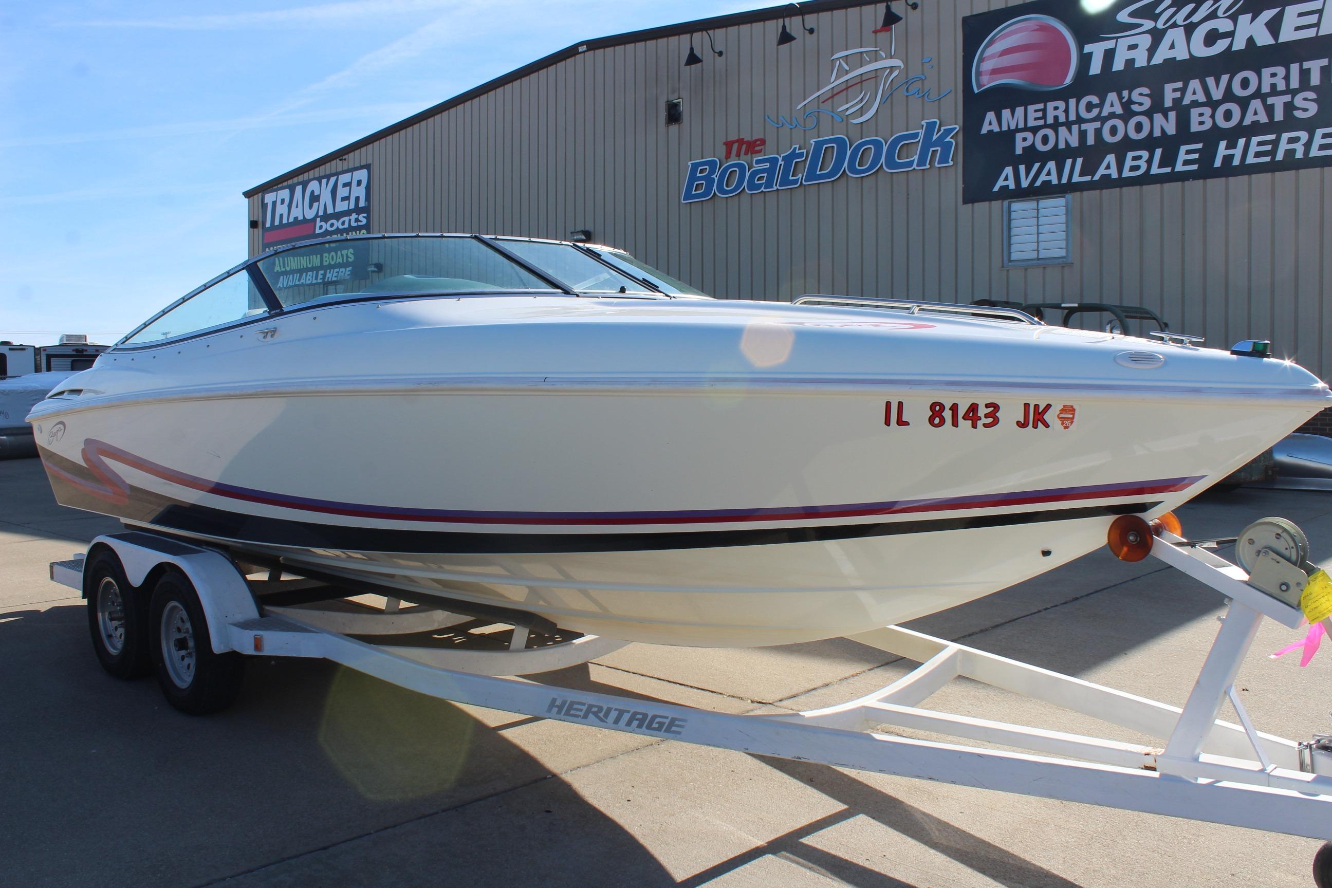 1996 Baja 232 speedboat on trailer at dealership, featuring sleek white design.