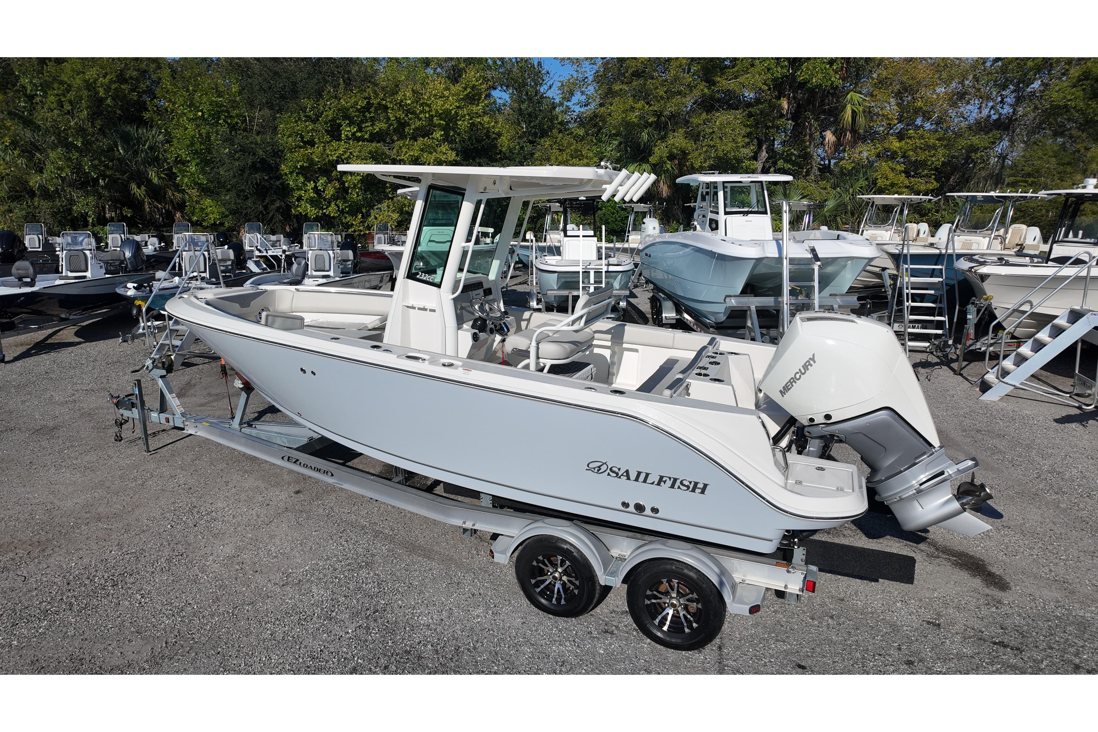 A Sailfish 232 CC boat on a trailer, surrounded by other boats and trees.