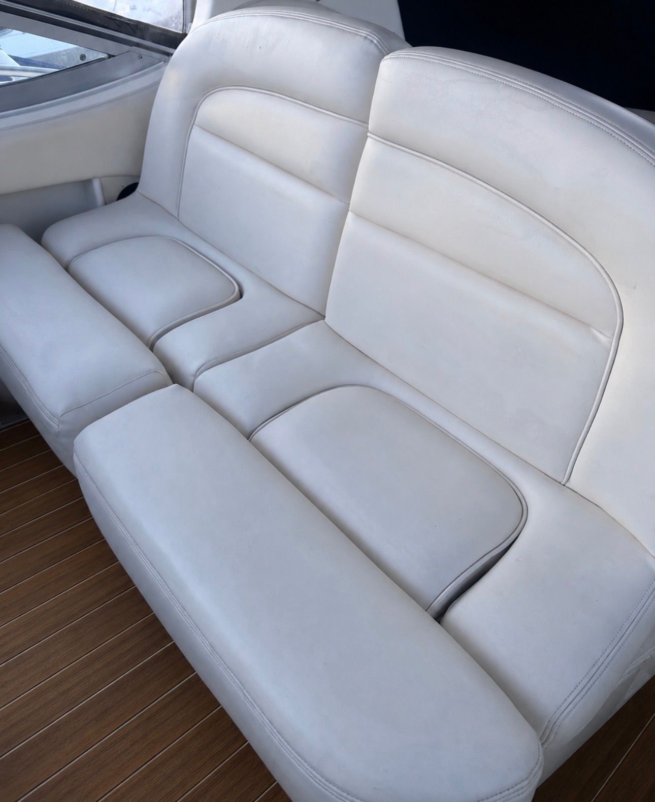 White leather seating on a boat with wooden flooring.