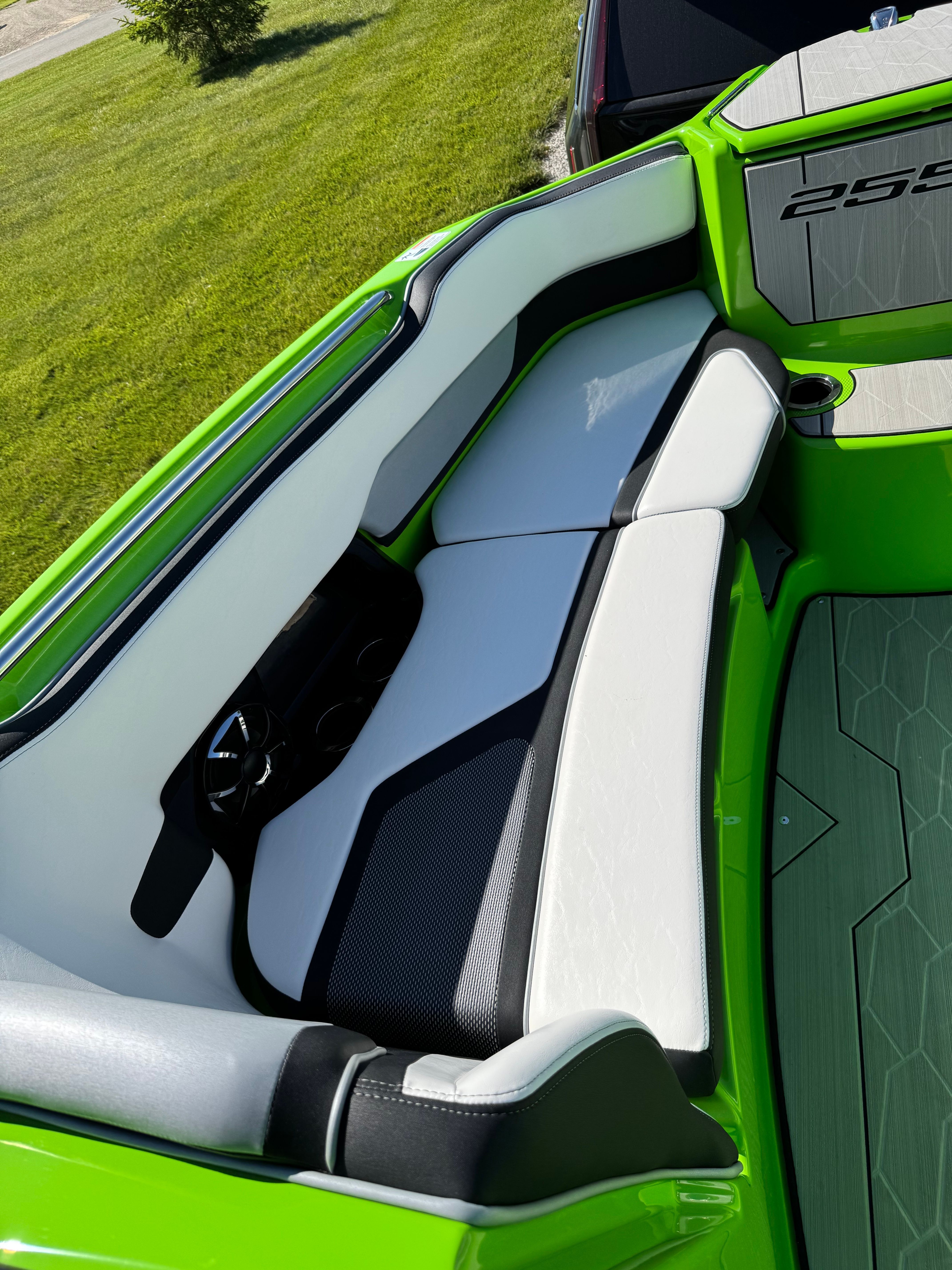 Green and white boat with cushioned seating and cup holders.