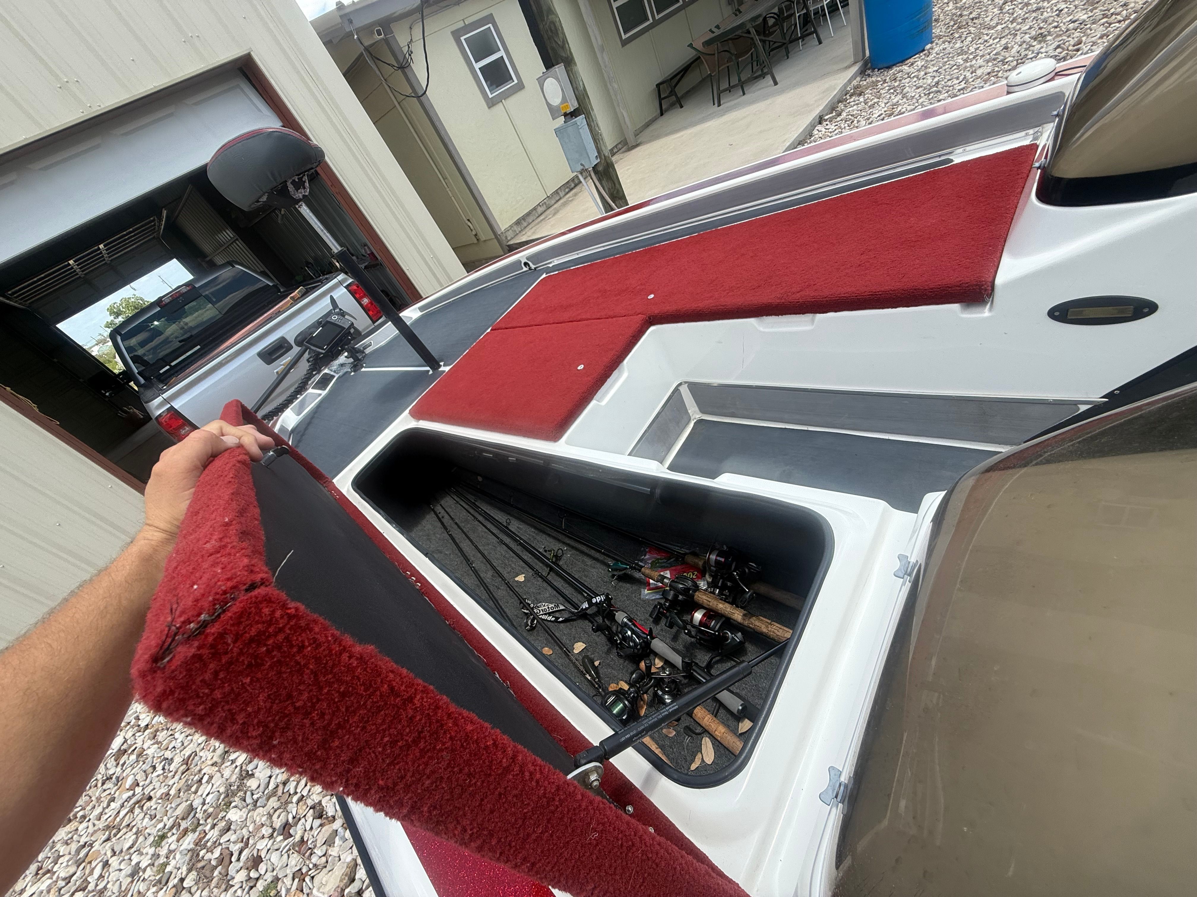 A 1999 Champion 202 boat with red upholstery and storage for fishing rods.