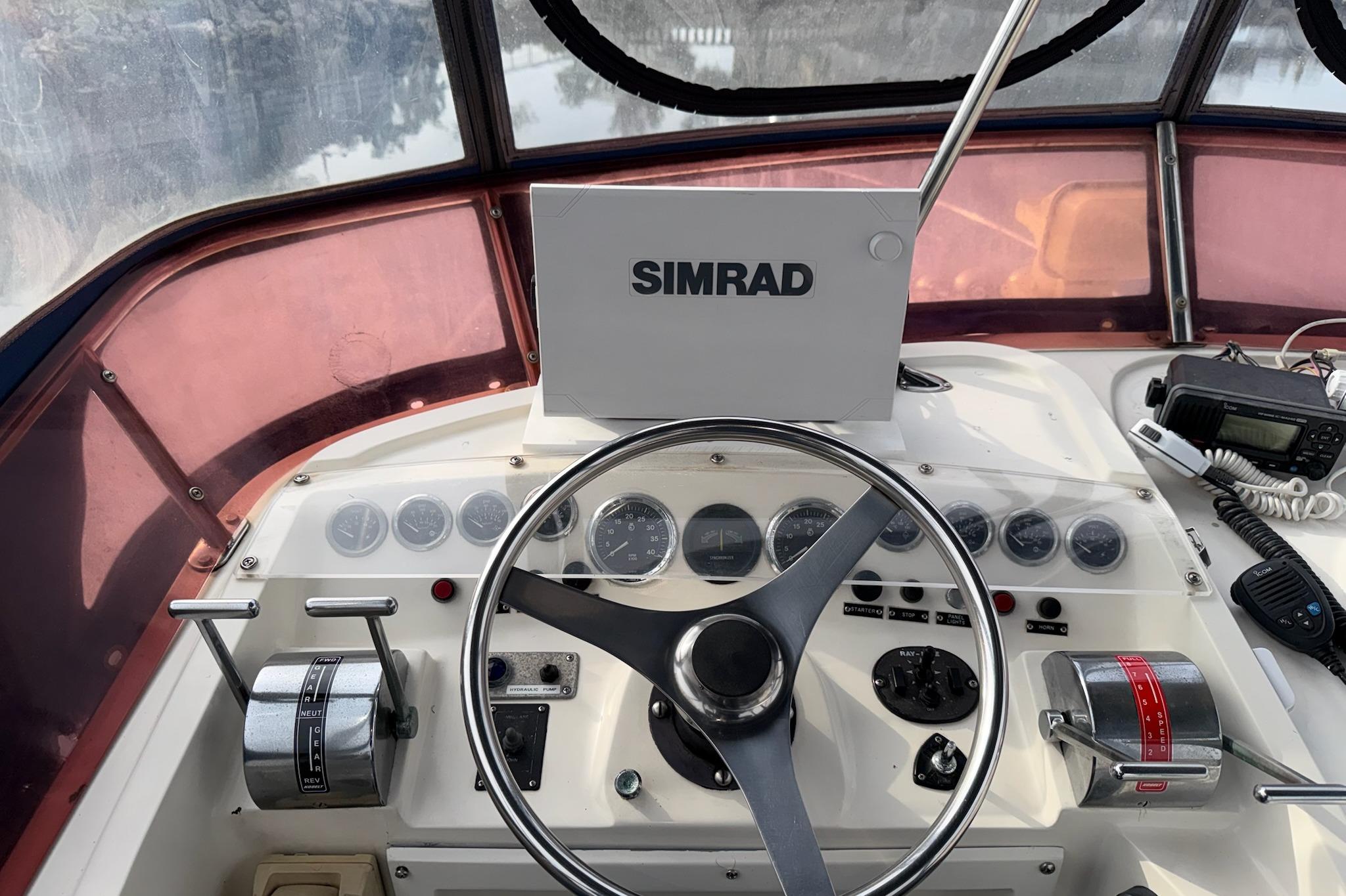 Cockpit of a 1990 Mediterranean Sport Fish boat with steering wheel and navigation equipment.