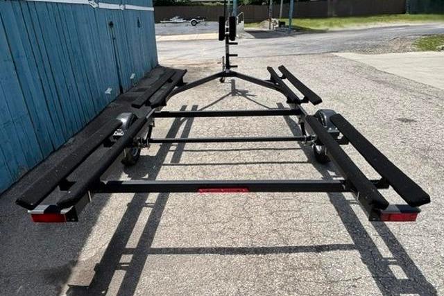2023 Yacht Club 18' Pontoon trailer on pavement, near blue building.