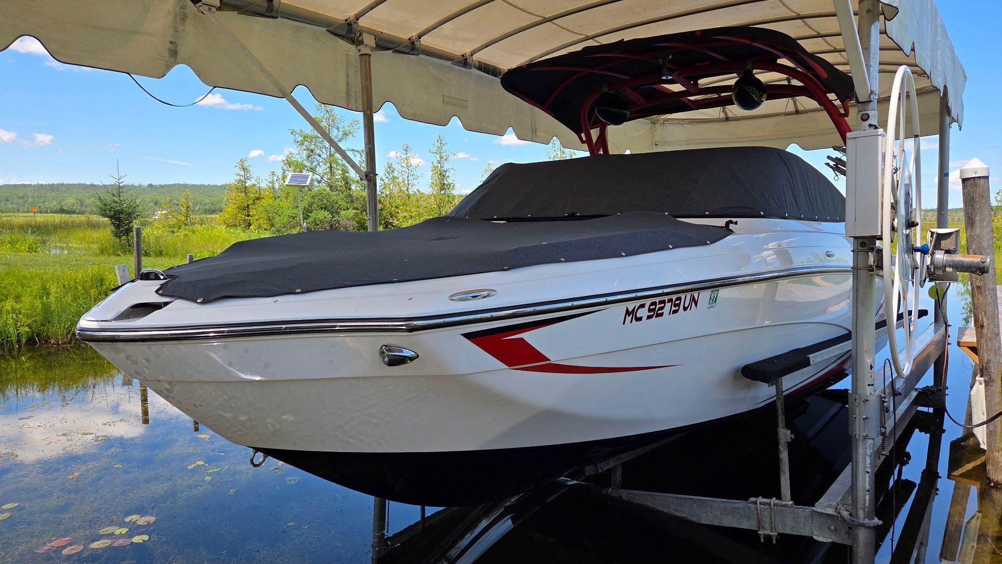 A 2018 Yamaha 242X E-Series boat is on a lift under a canopy.