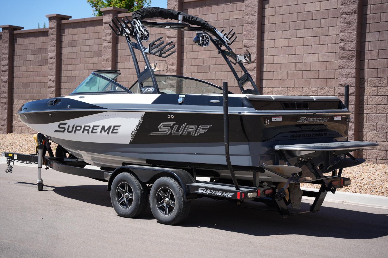 2016 Supreme S211 boat on trailer, parked near brick wall.