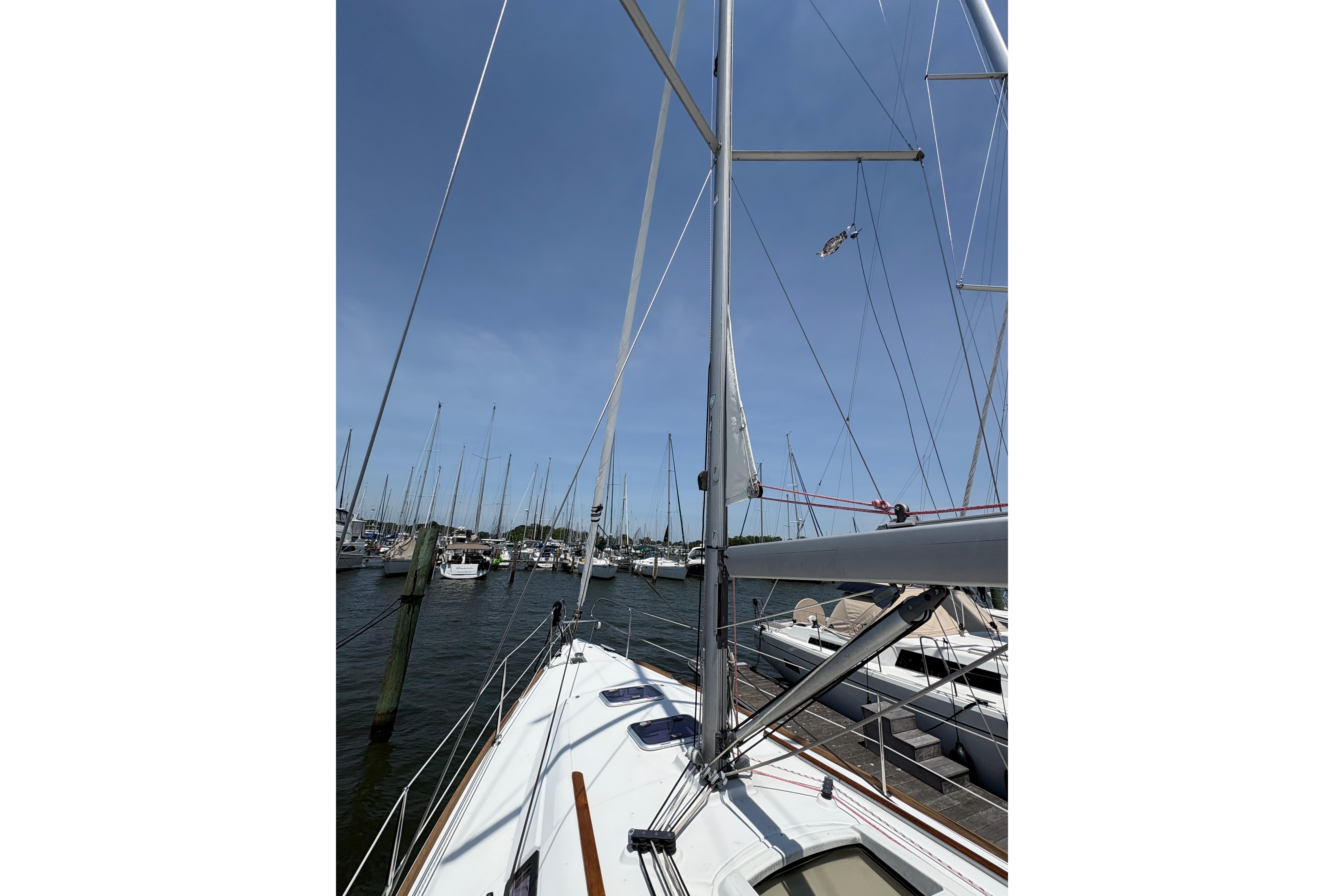 Sailboat Beneteau Oceanis 34, 2015 model, docked in a marina under clear blue skies.