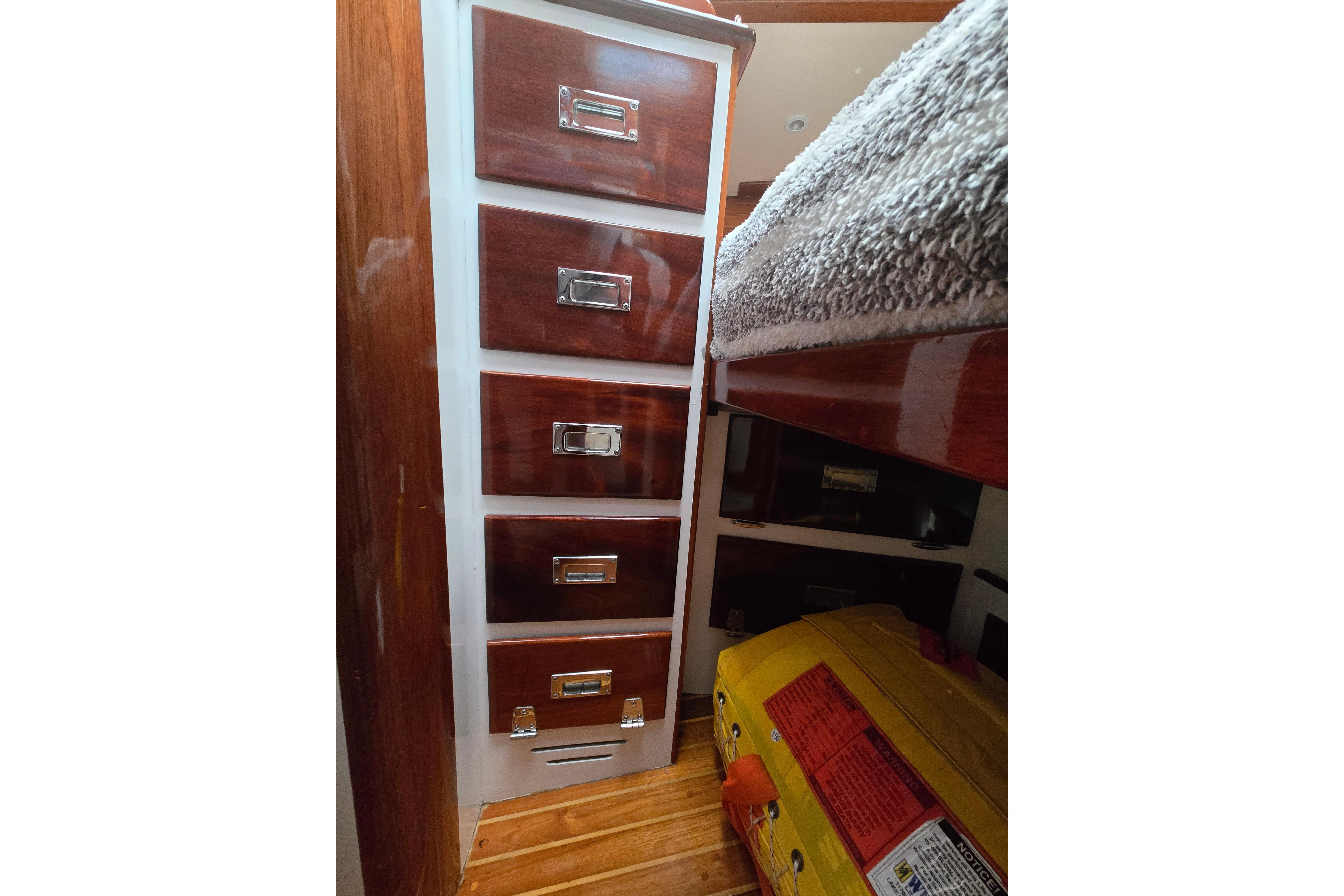 Interior of 1970 Hinckley Bermuda 40 with wooden drawers and cozy bedding.
