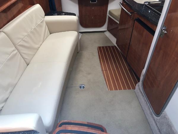 Interior of a 2008 Four Winns V338 with cream sofa and wooden cabinetry.