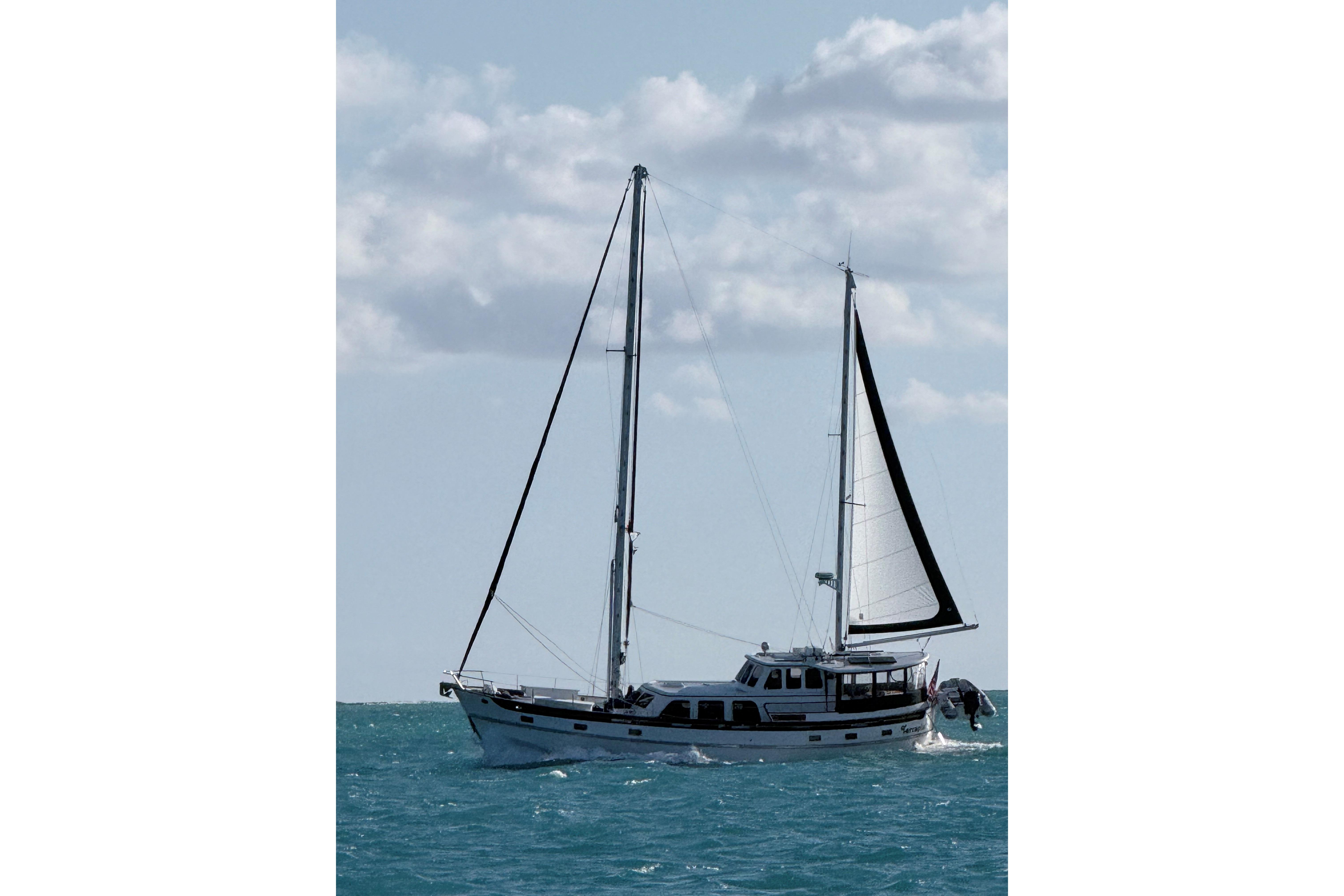 1980 Cheoy Lee 52 Motorsailer sailing on open sea under cloudy sky.