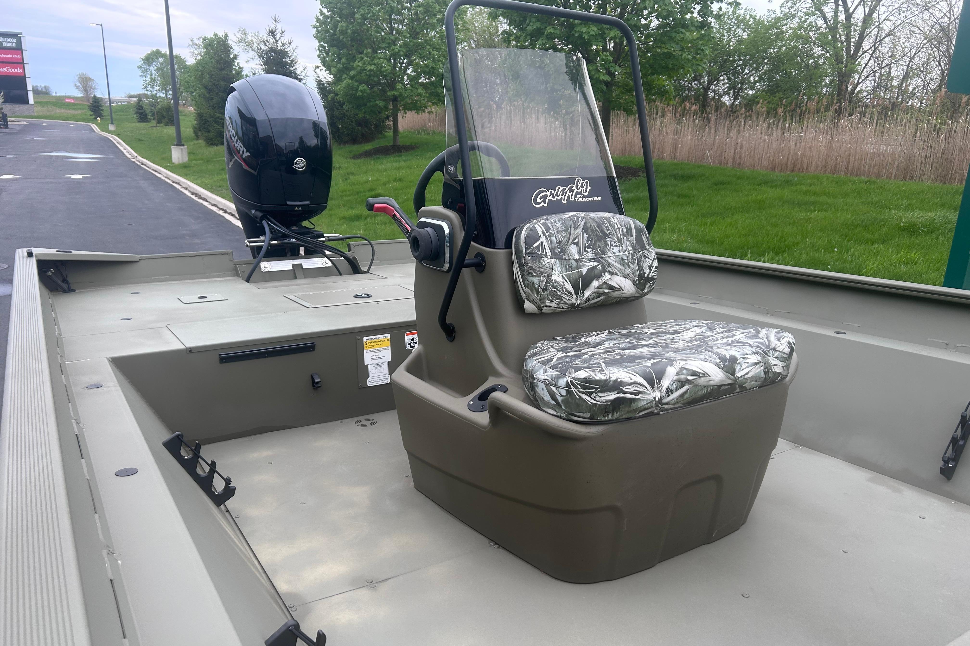 2024 Tracker Grizzly 2072 CC boat with camo seats and outboard motor, parked outdoors.