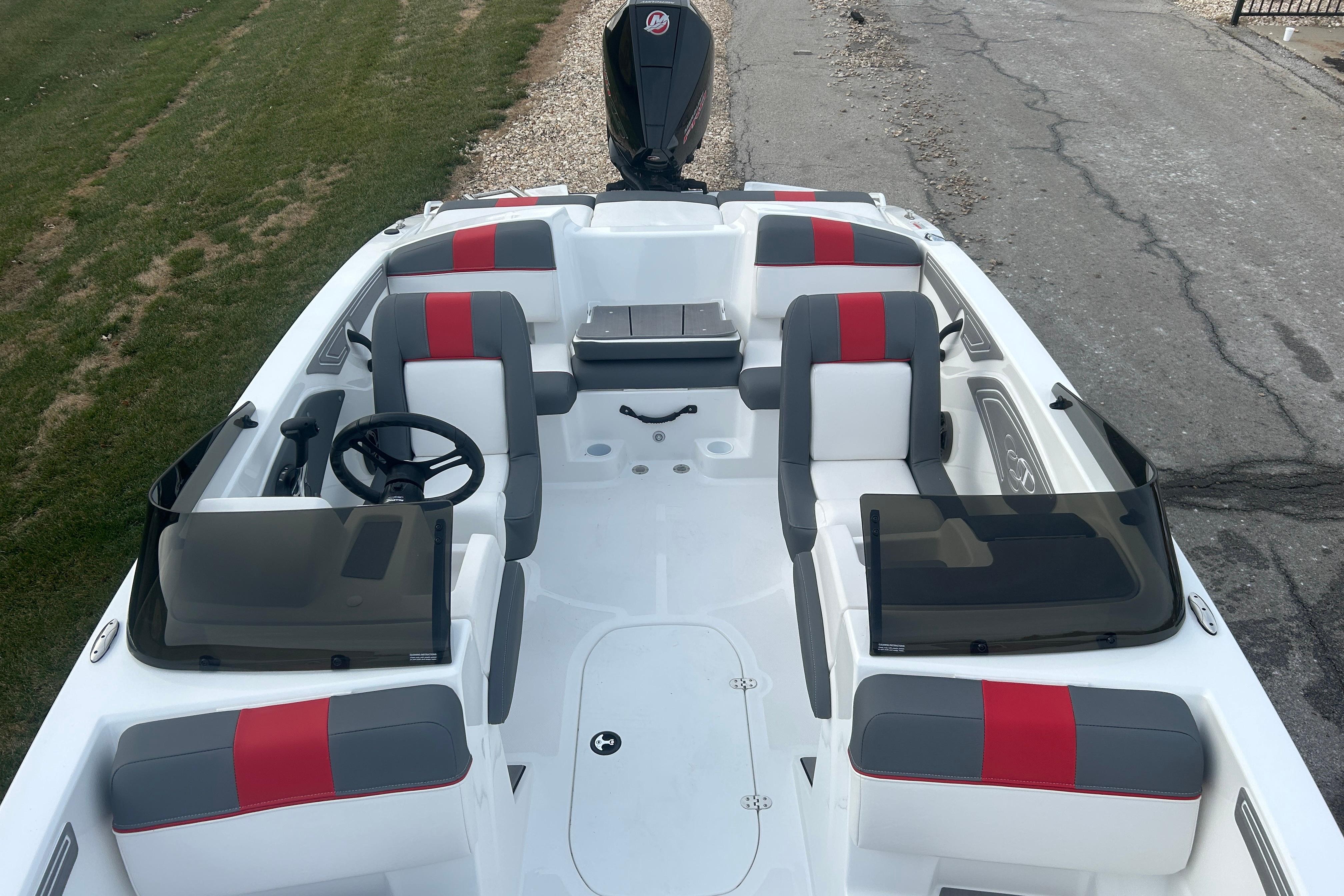 2025 Tahoe T21 boat interior with gray and red seating, steering wheel, and windshield.