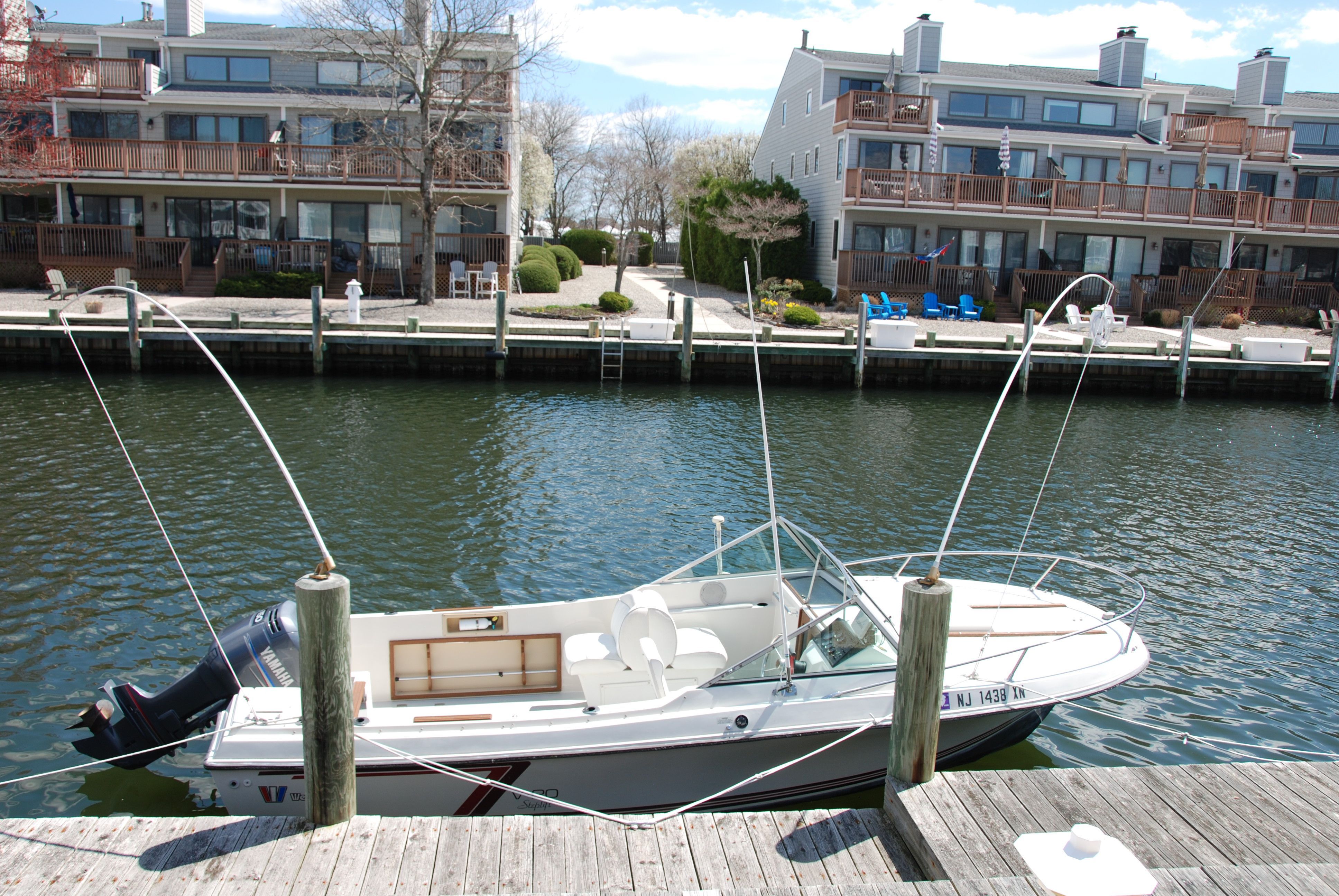 A 1987 Wellcraft V-20 Steplift docked in a calm canal near waterfront homes.