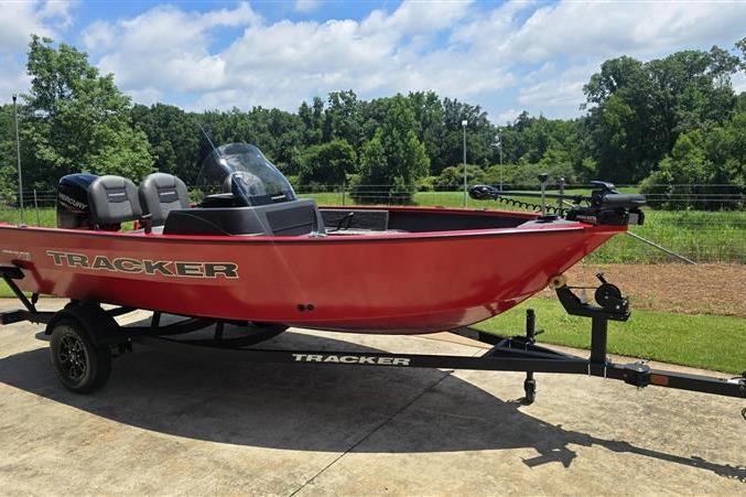 2026 Tracker Pro Guide V-16 SC boat in vibrant red on a trailer, parked outdoors.