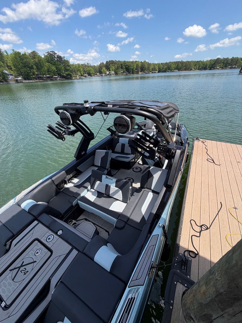 2023 MasterCraft X24 boat docked by a lake on a sunny day.