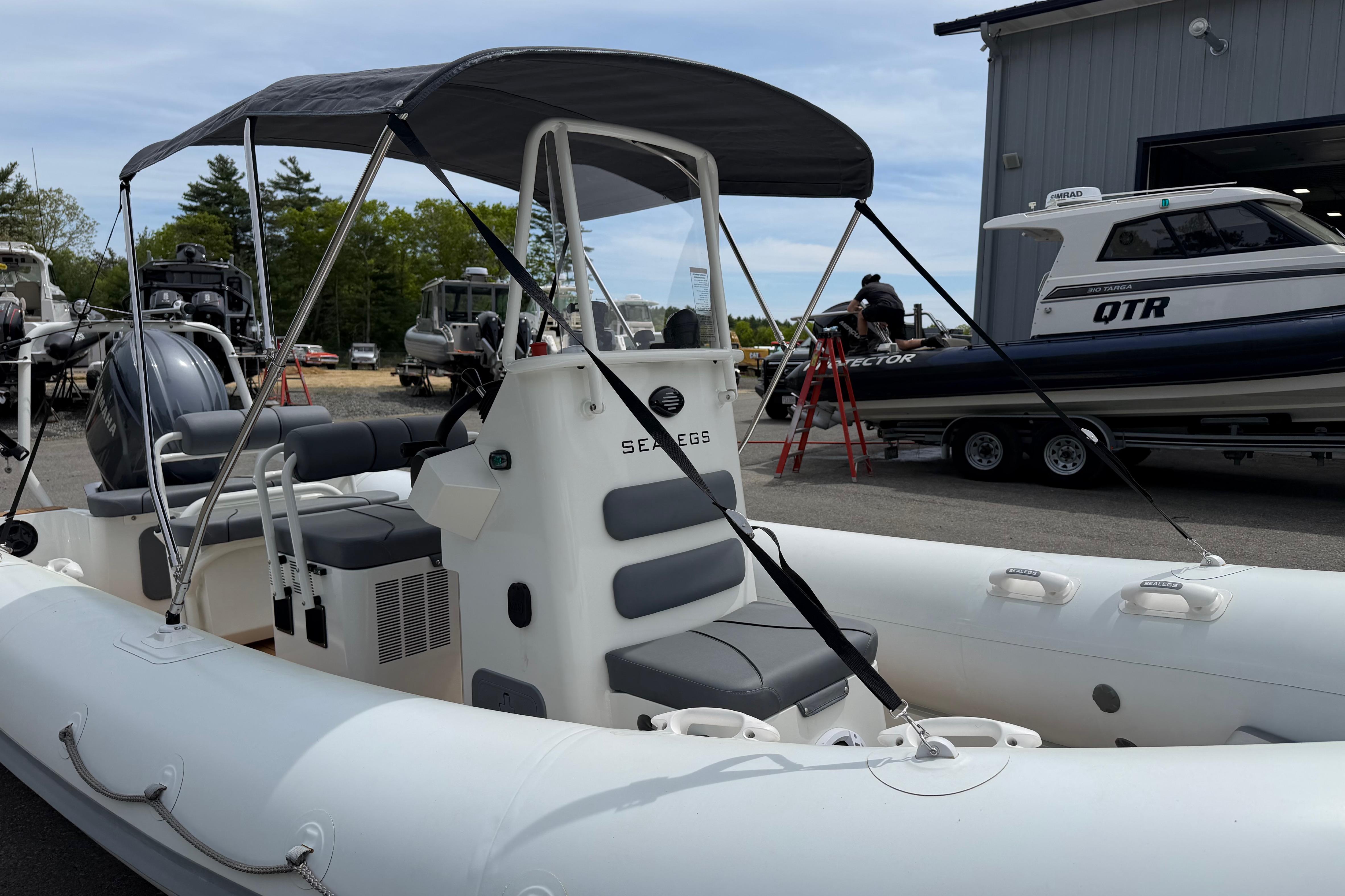2024 Sealegs 7.1m RIB boat with canopy, parked outdoors near other boats.