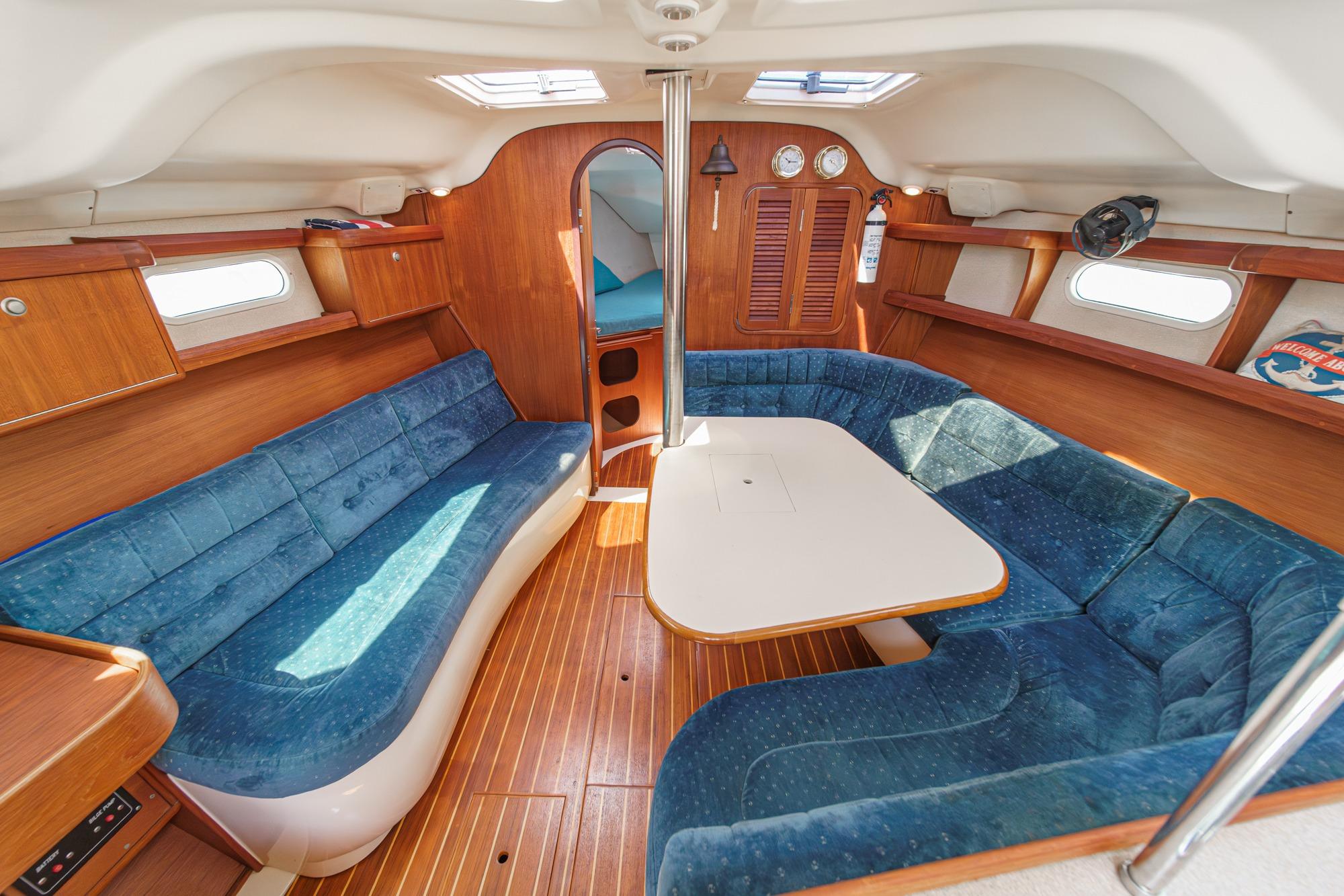 Interior of a 1996 Hunter 376 sailboat with blue seating and wooden accents.