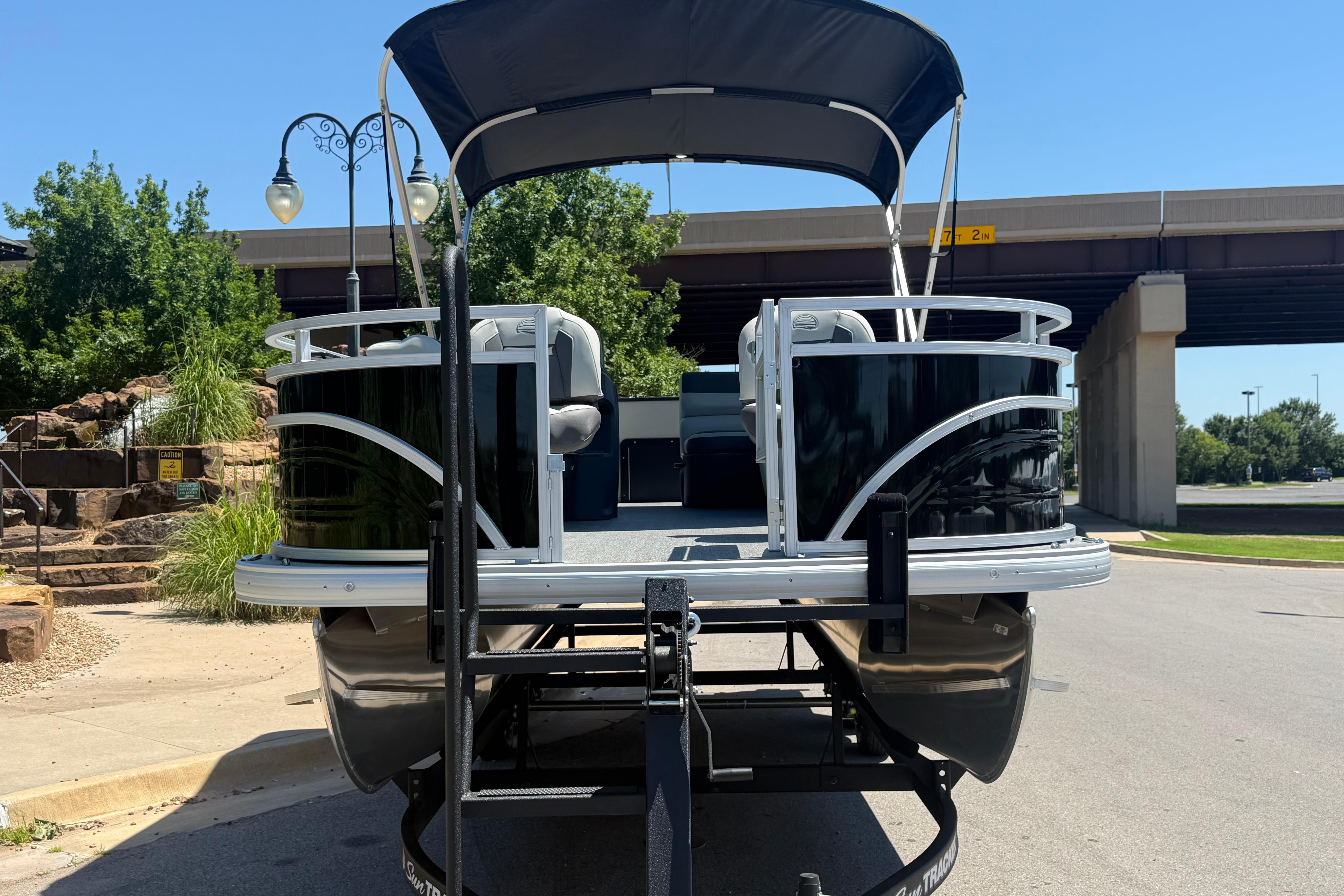2026 Sun Tracker Fishin' Barge 22 DLX pontoon boat on trailer, parked outdoors.