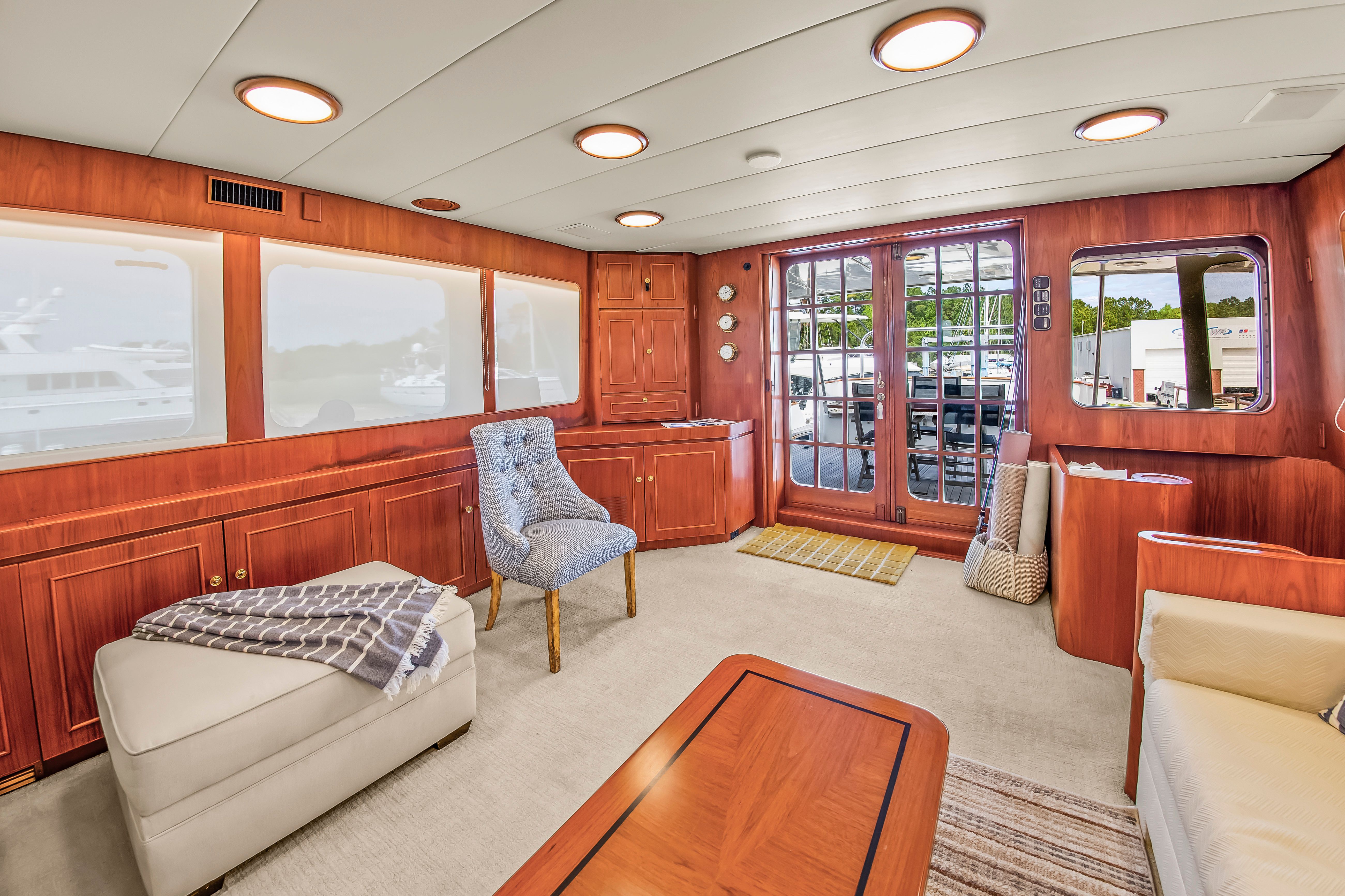 Interior of a 1987 Jongert 78 Motor Yacht with elegant wood furnishings and large windows.
