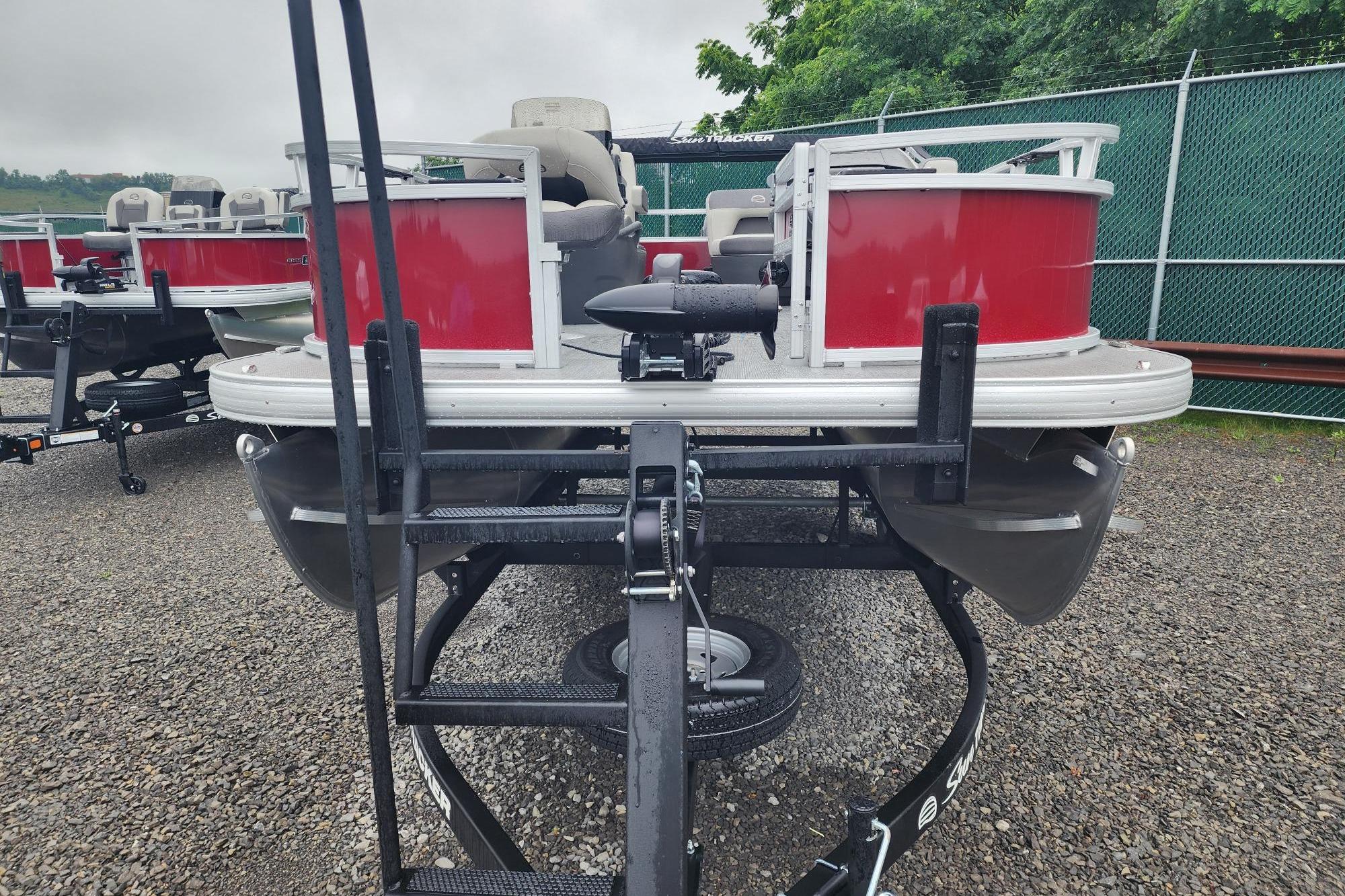 2026 Sun Tracker Bass Buggy 16 XL Select pontoon boat on trailer, red and silver design.