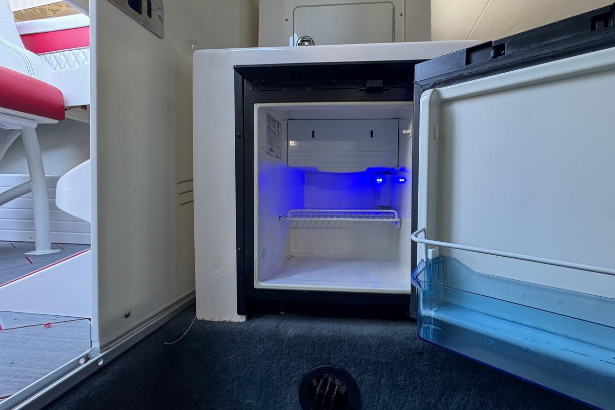 Open mini fridge with blue interior light in 2022 Velocity 290sc boat.