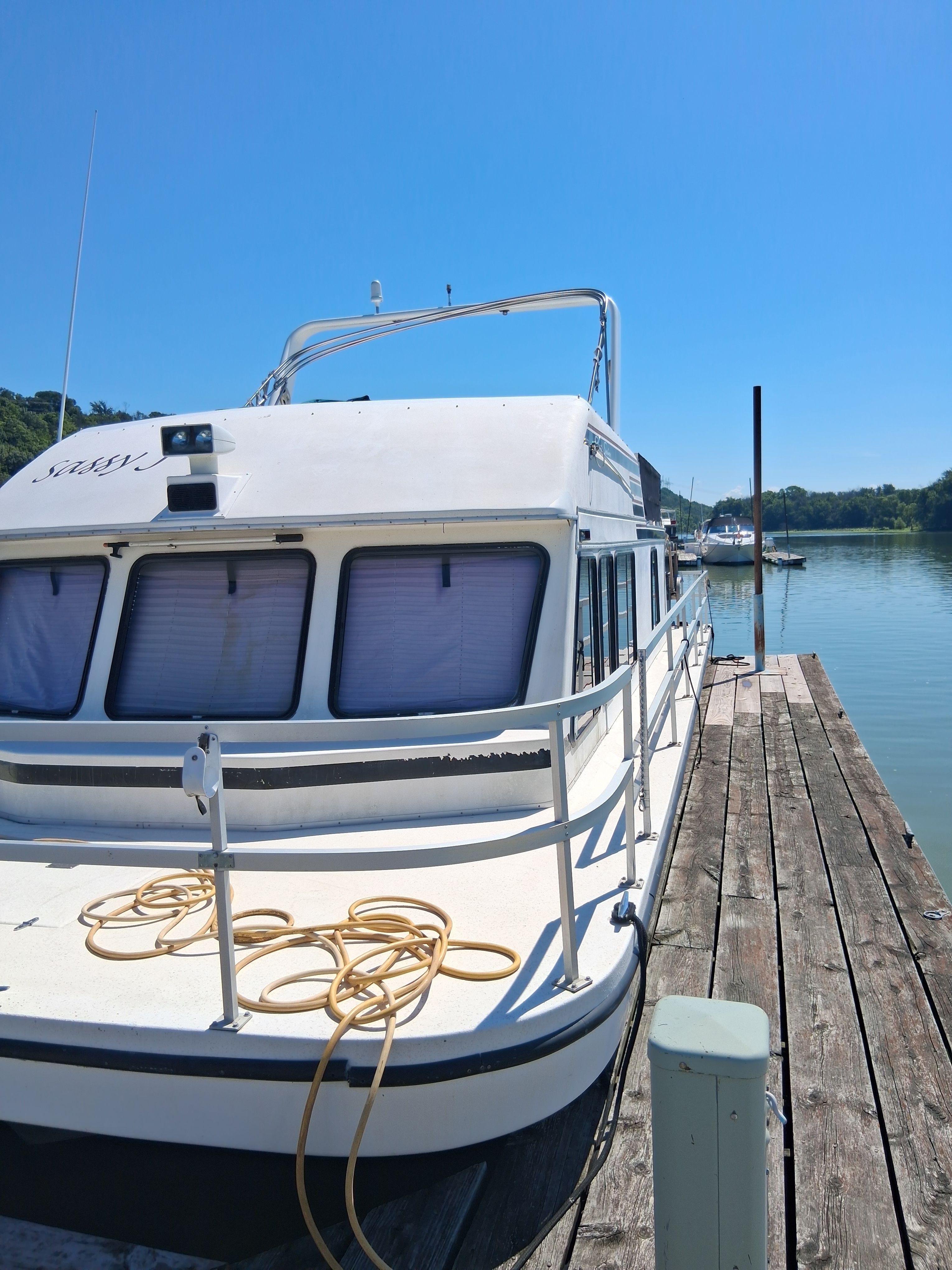 A 1993 Gibson 370 Sport docked at a wooden pier. The sky is clear and blue.