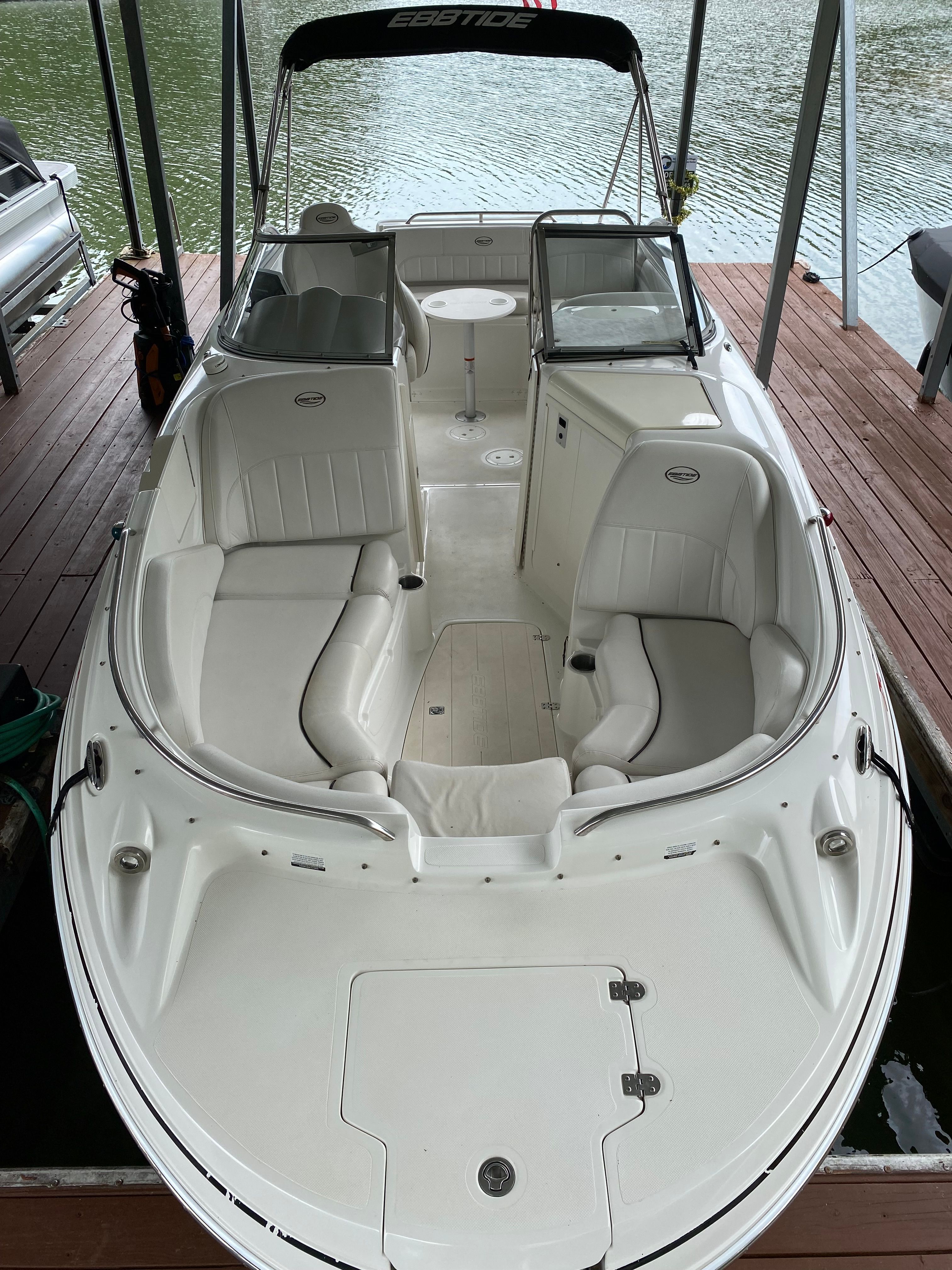 A 2007 Ebbtide 2460 Z-Trak boat with white interior seating, docked by the water.