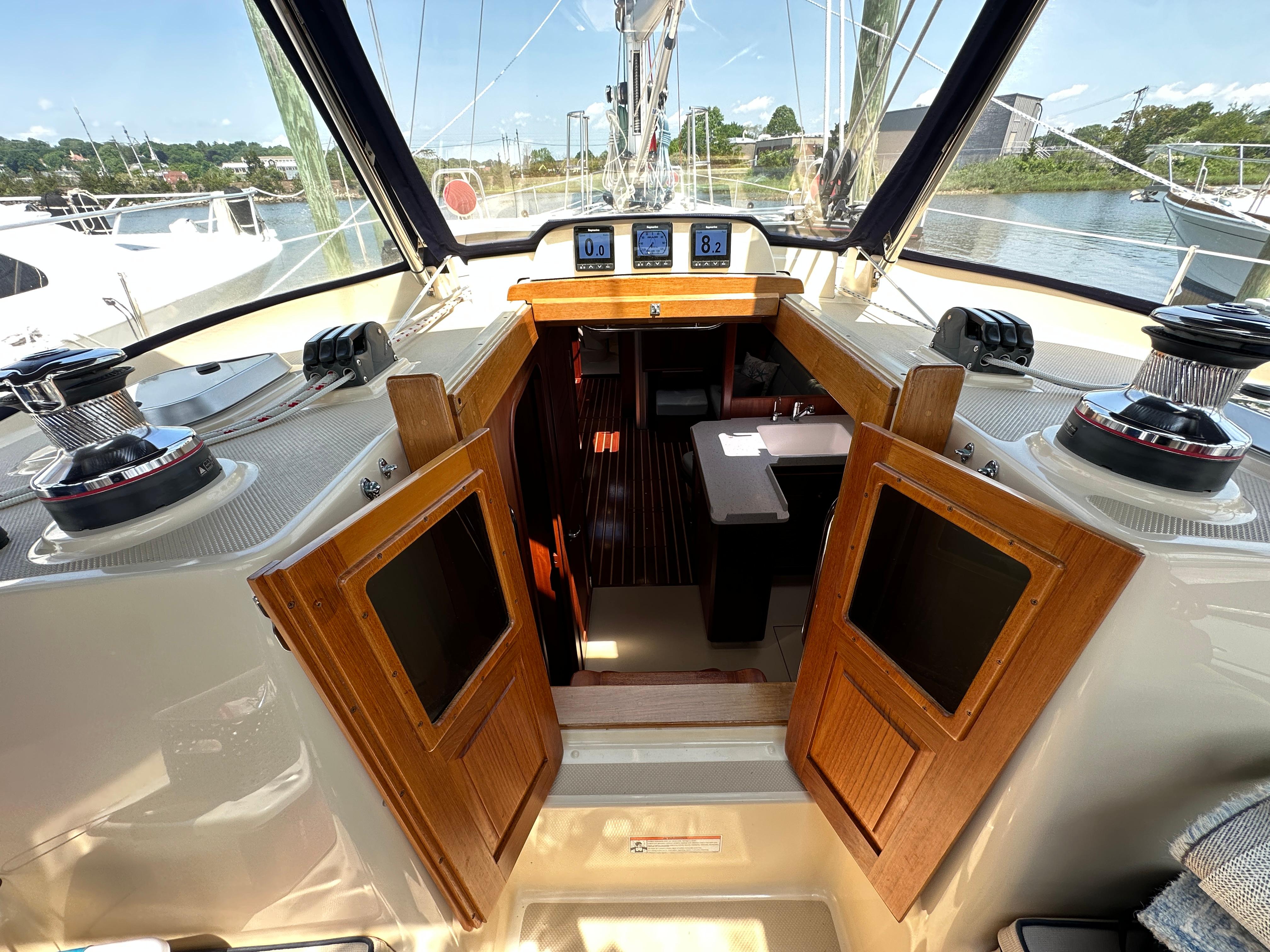 Cockpit view of 2021 Island Packet 439 sailboat, showcasing navigation instruments and wooden cabin doors.