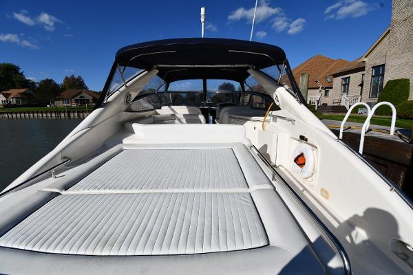 1997 Sunseeker Camargue 47 yacht with spacious deck and sleek design, docked near waterfront homes.