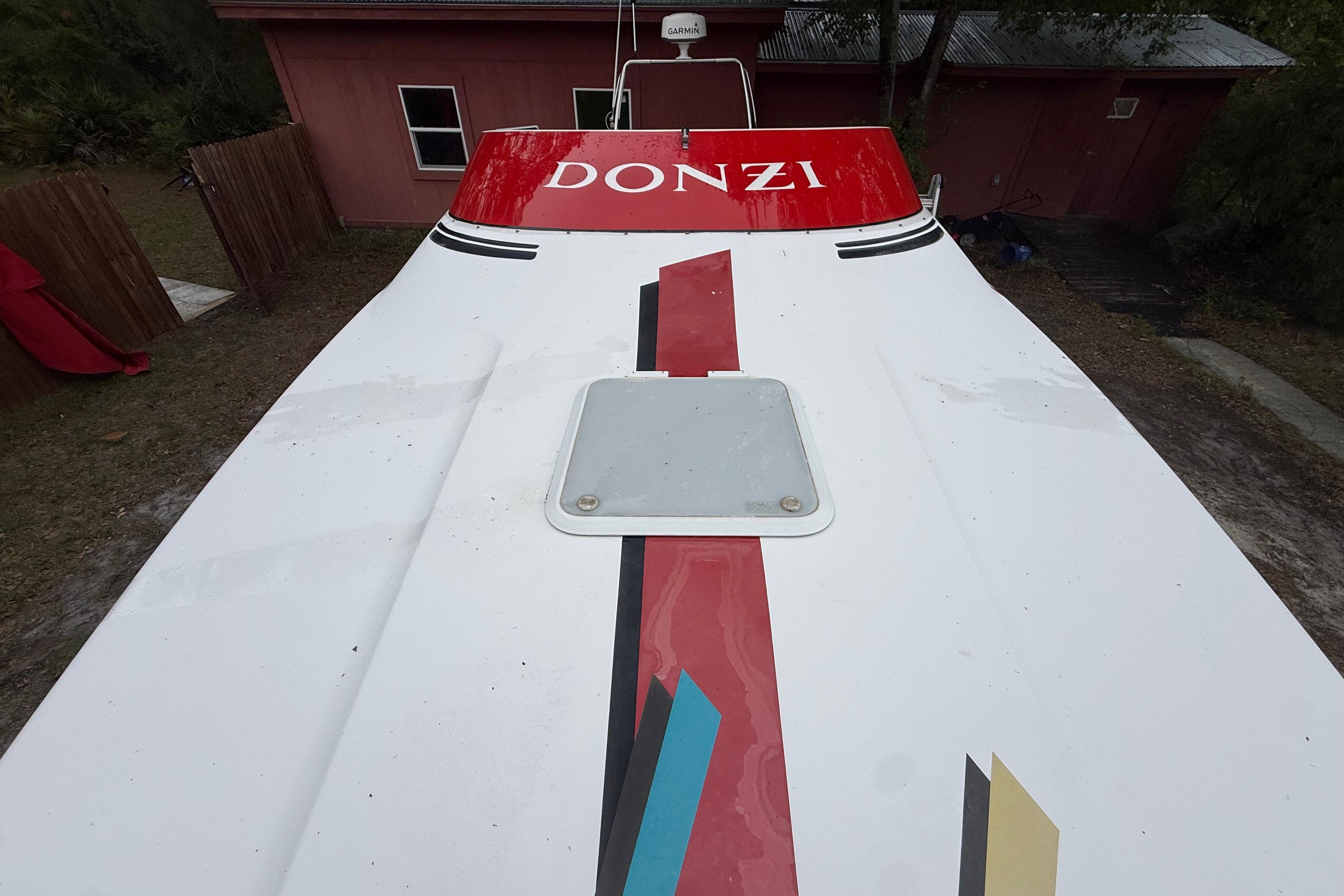 1998 Donzi 33 ZX boat with colorful graphics, parked near a red building.