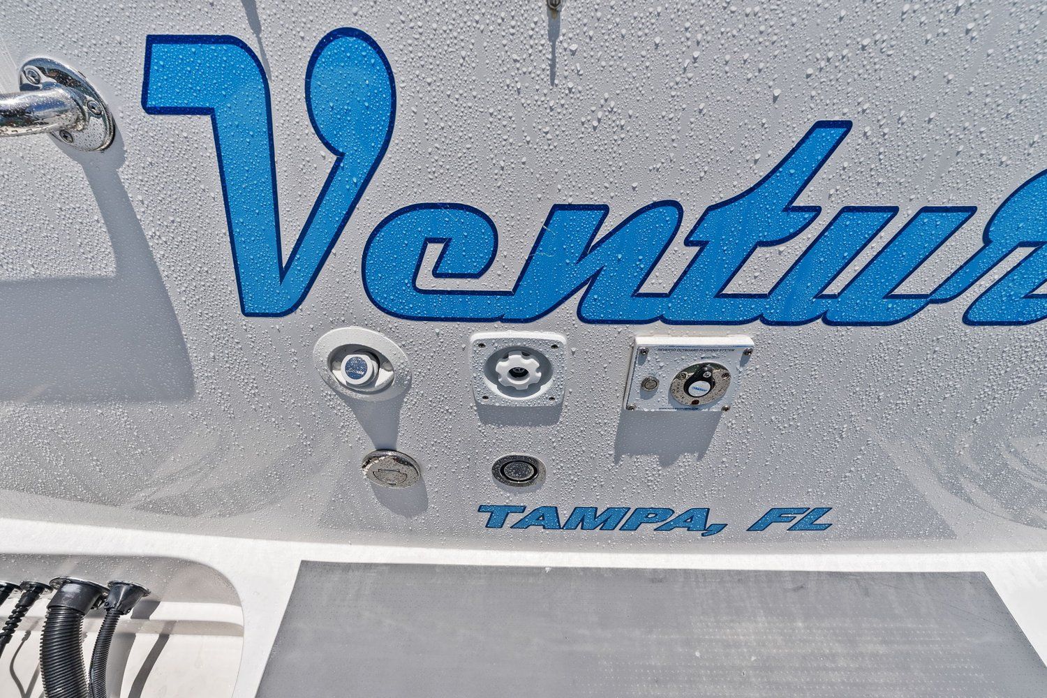 Close-up of boat hull with blue lettering and fittings, "Tampa, FL" below.