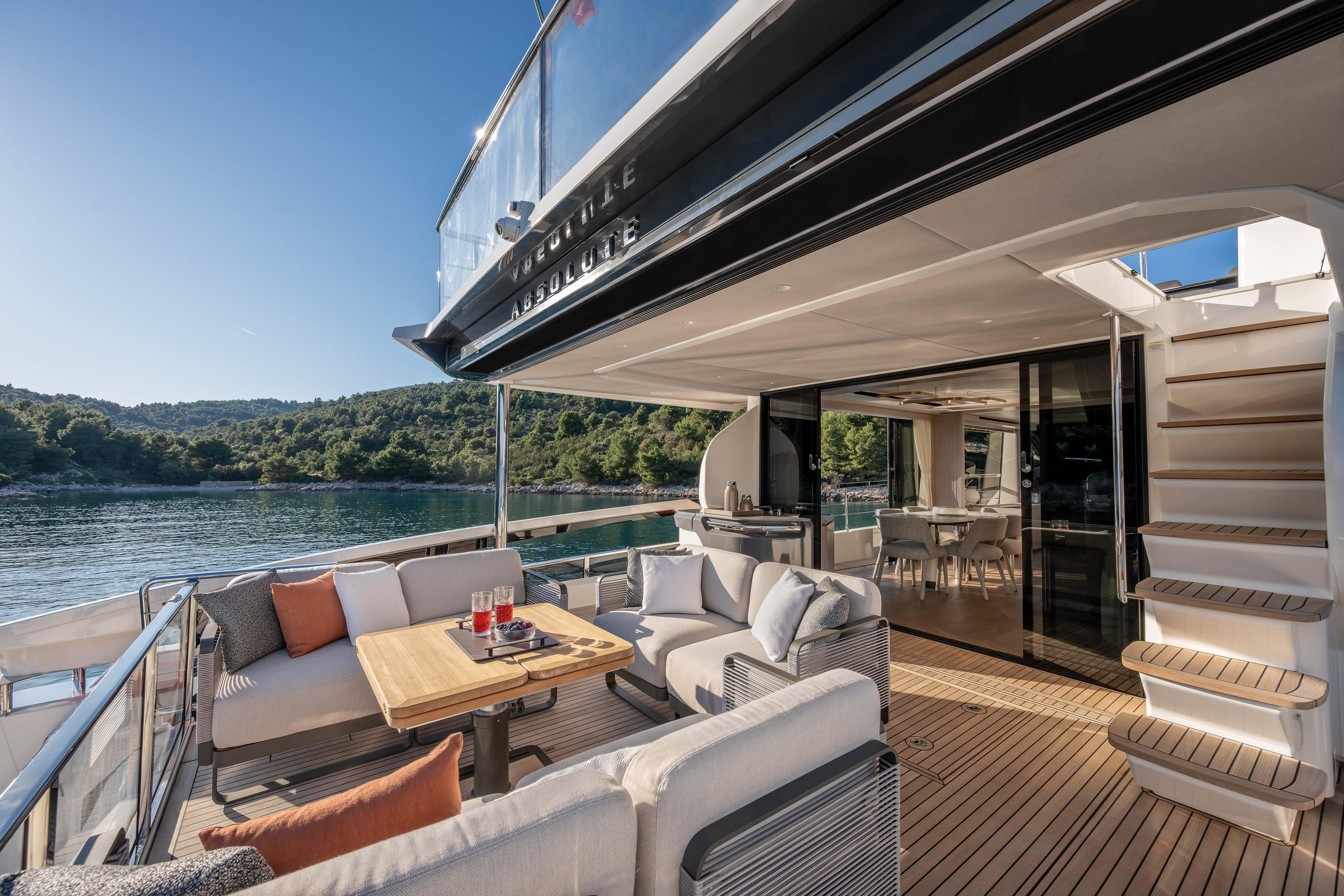 Luxurious yacht with stylish deck, comfortable seating, and view of wooded coastline.