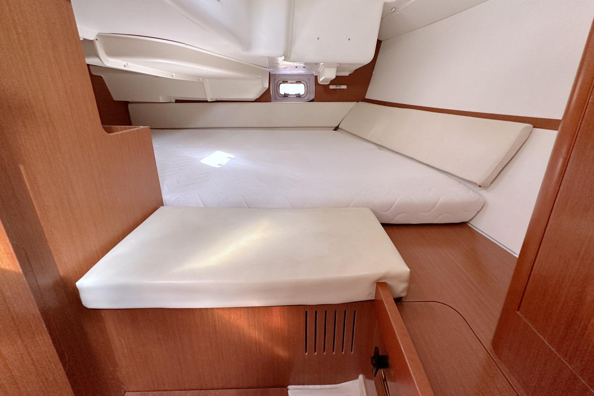 Interior cabin of 2014 Beneteau Oceanis 34 sailboat, featuring a cozy bed and wooden finish.