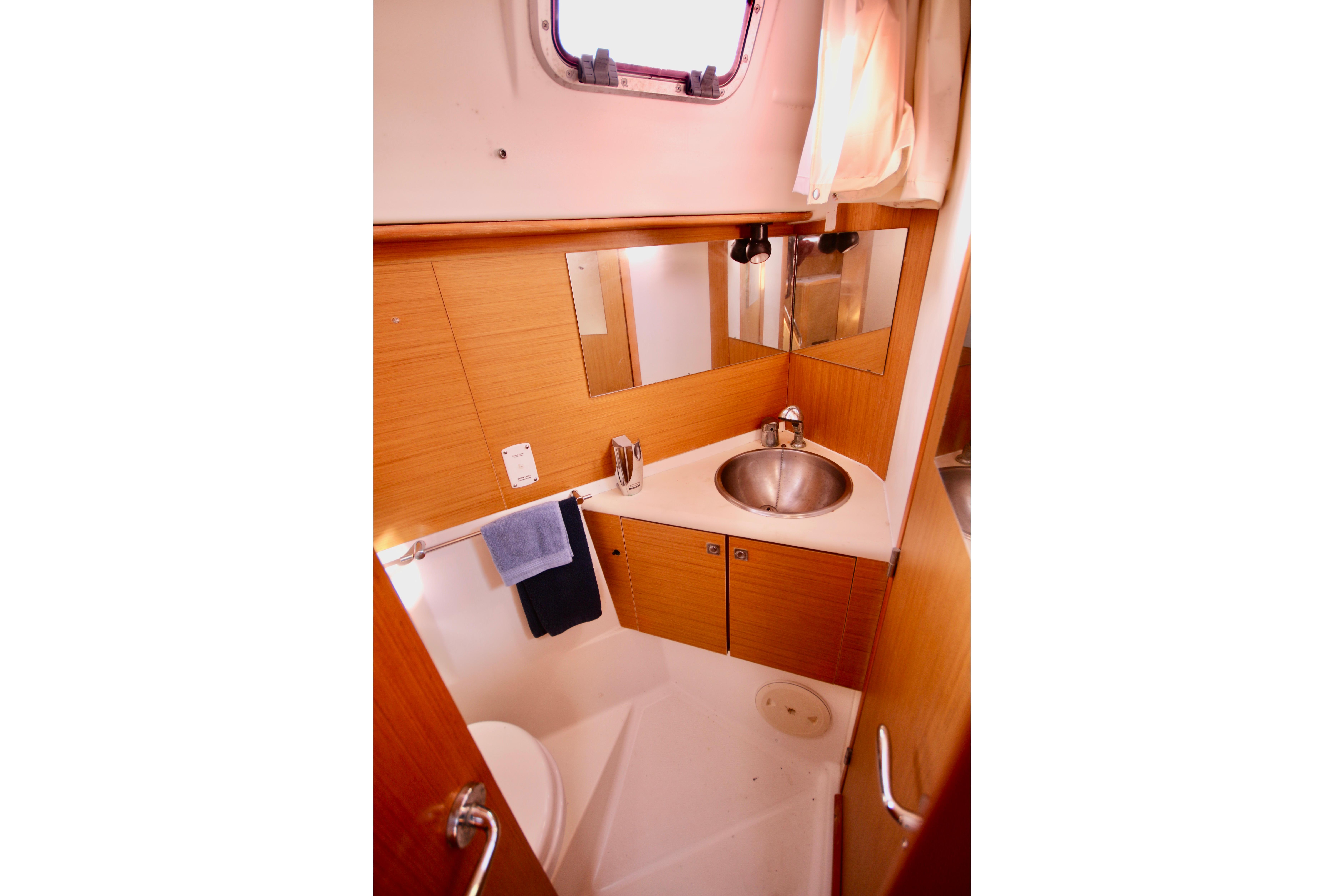 2009 Jeanneau Sun Odyssey 44i yacht bathroom with sink, mirror, and wooden cabinetry.